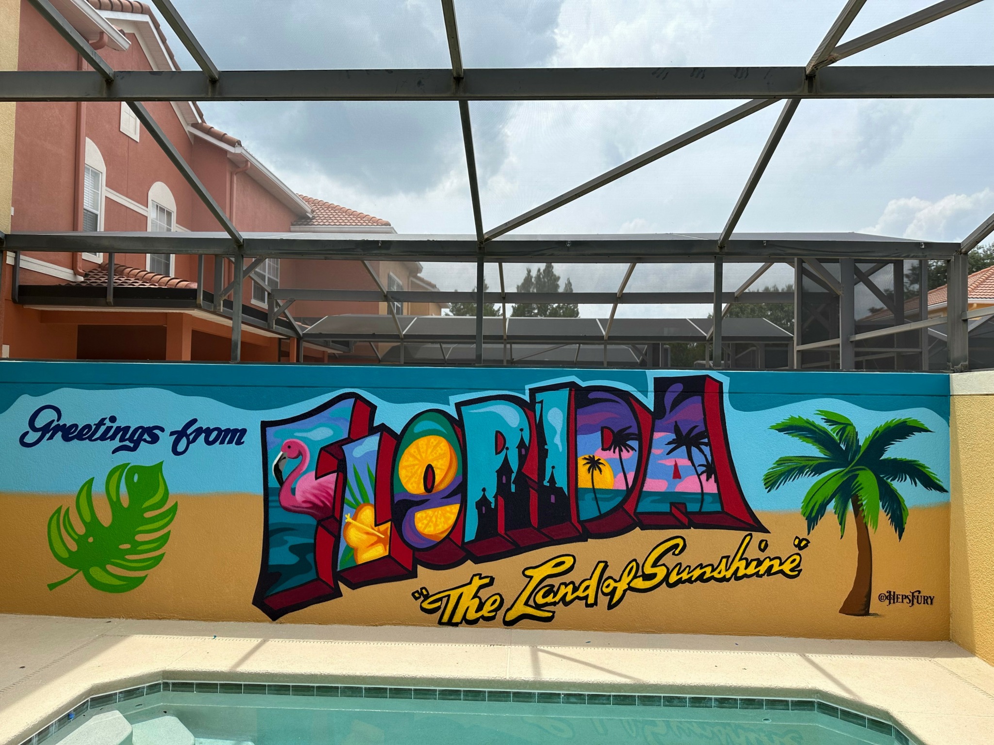 Colorful mural with the word 'Florida' and a palm tree, on a wall near a pool area.