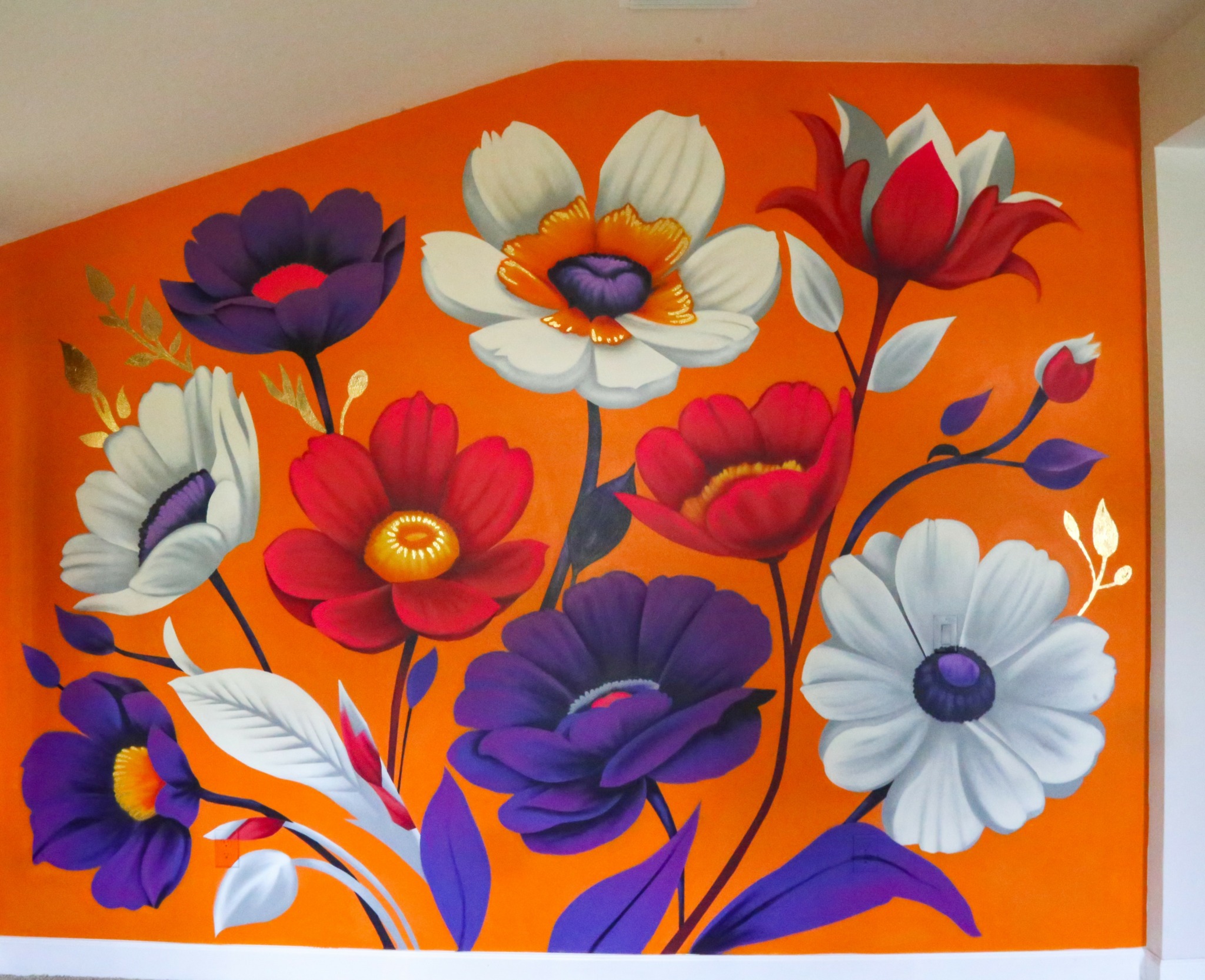 Bright orange wall with large, colorful flowers in purple, white, red, and yellow, with green leaves.