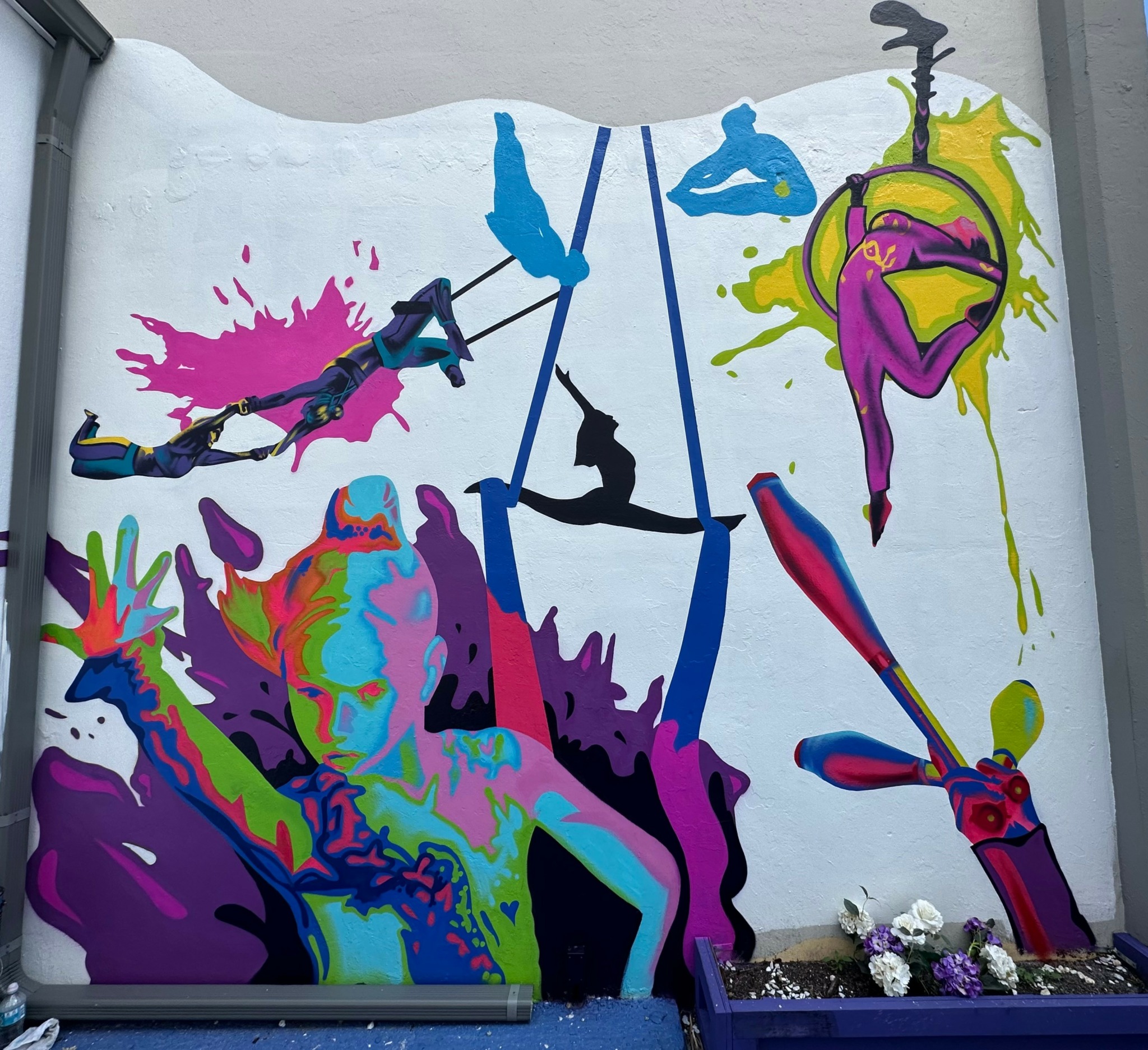 Colorful graffiti mural with abstract figures, spray paint splashes, and a person holding a spray can.
