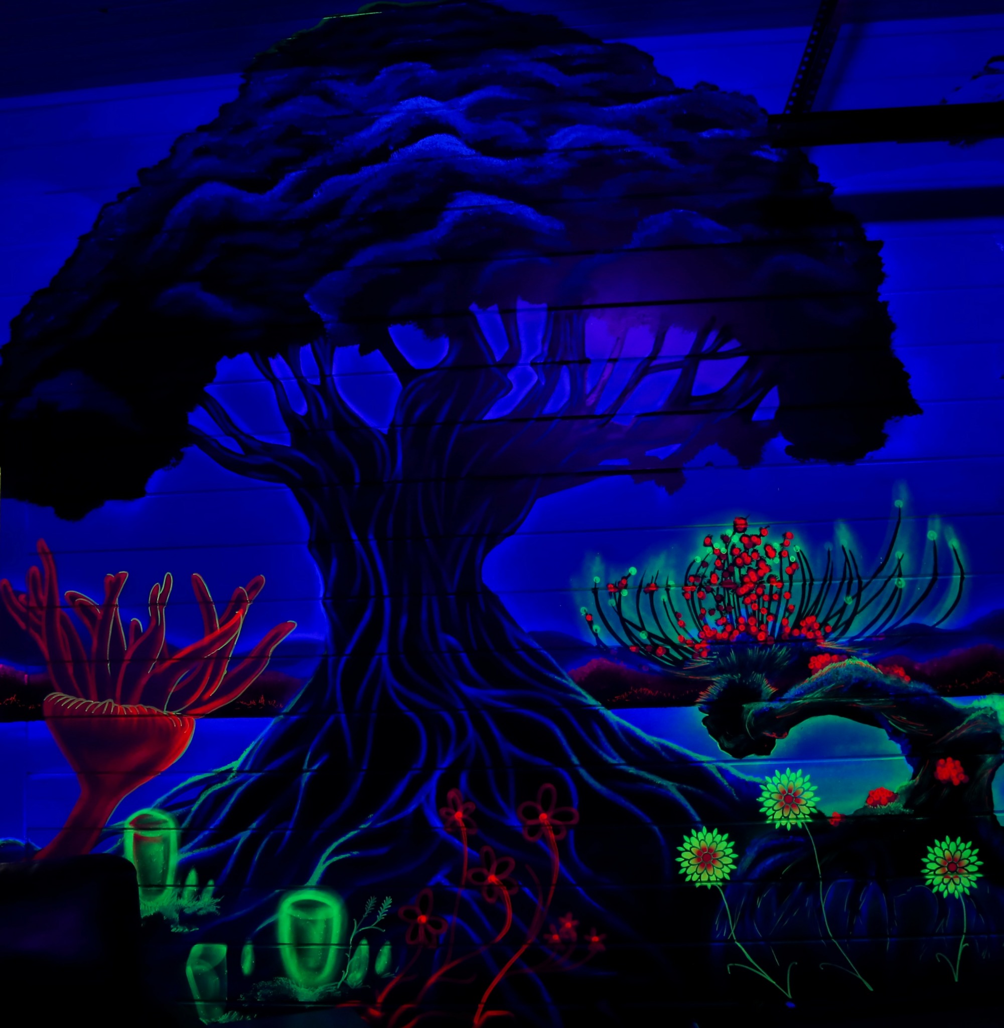 Glowing fantasy scene with a large tree, colorful flowers, and plants in a dark environment.