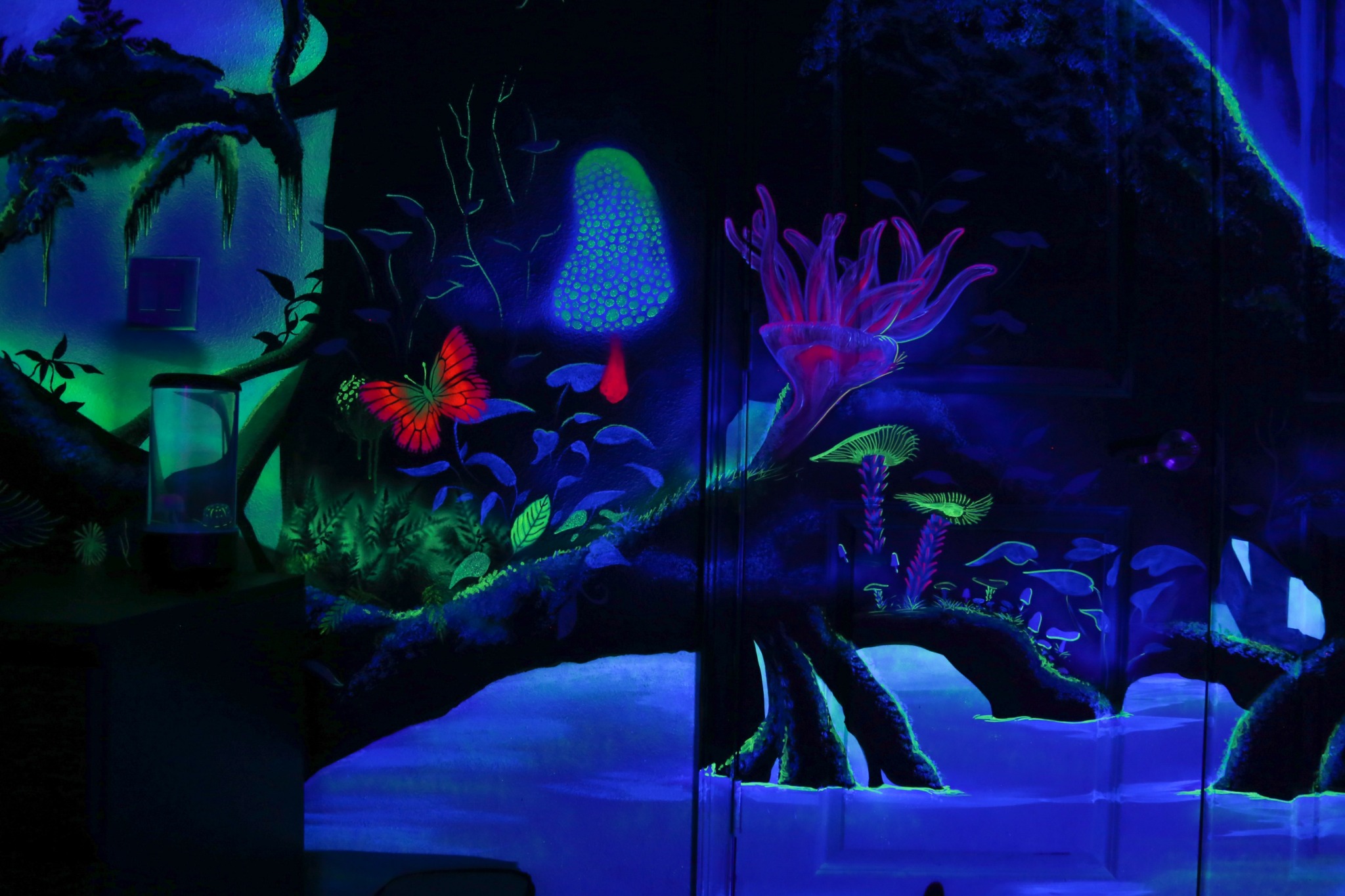 Colorful glowing plants and mushrooms in a dark, fantasy-like forest scene with a stream and vibrant flora.
