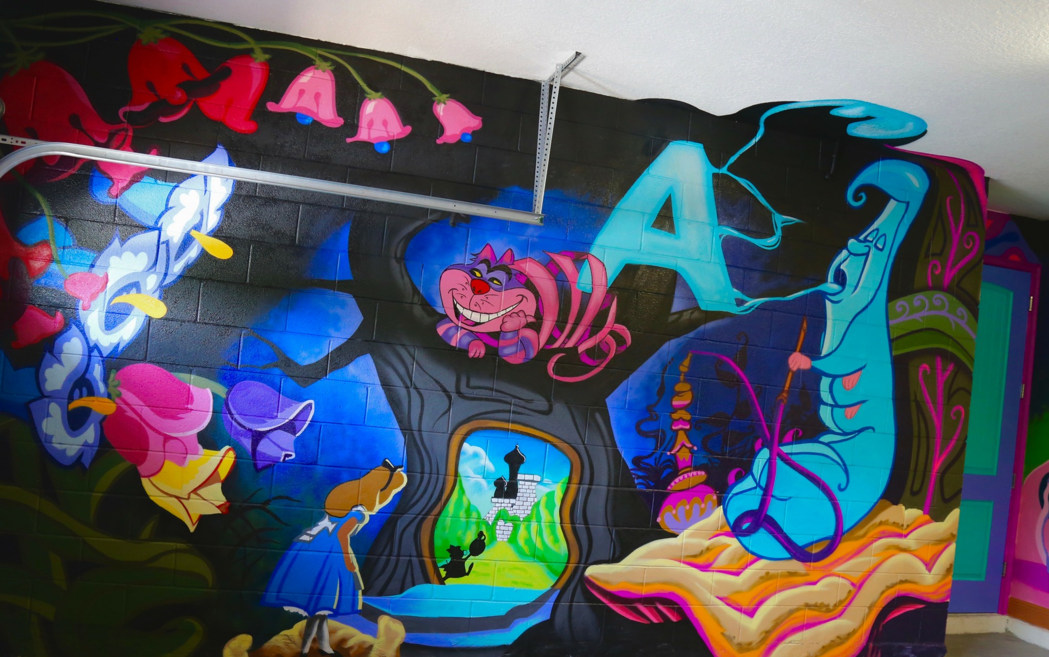 Colorful mural with cartoon characters, animals, and abstract shapes on a wall.