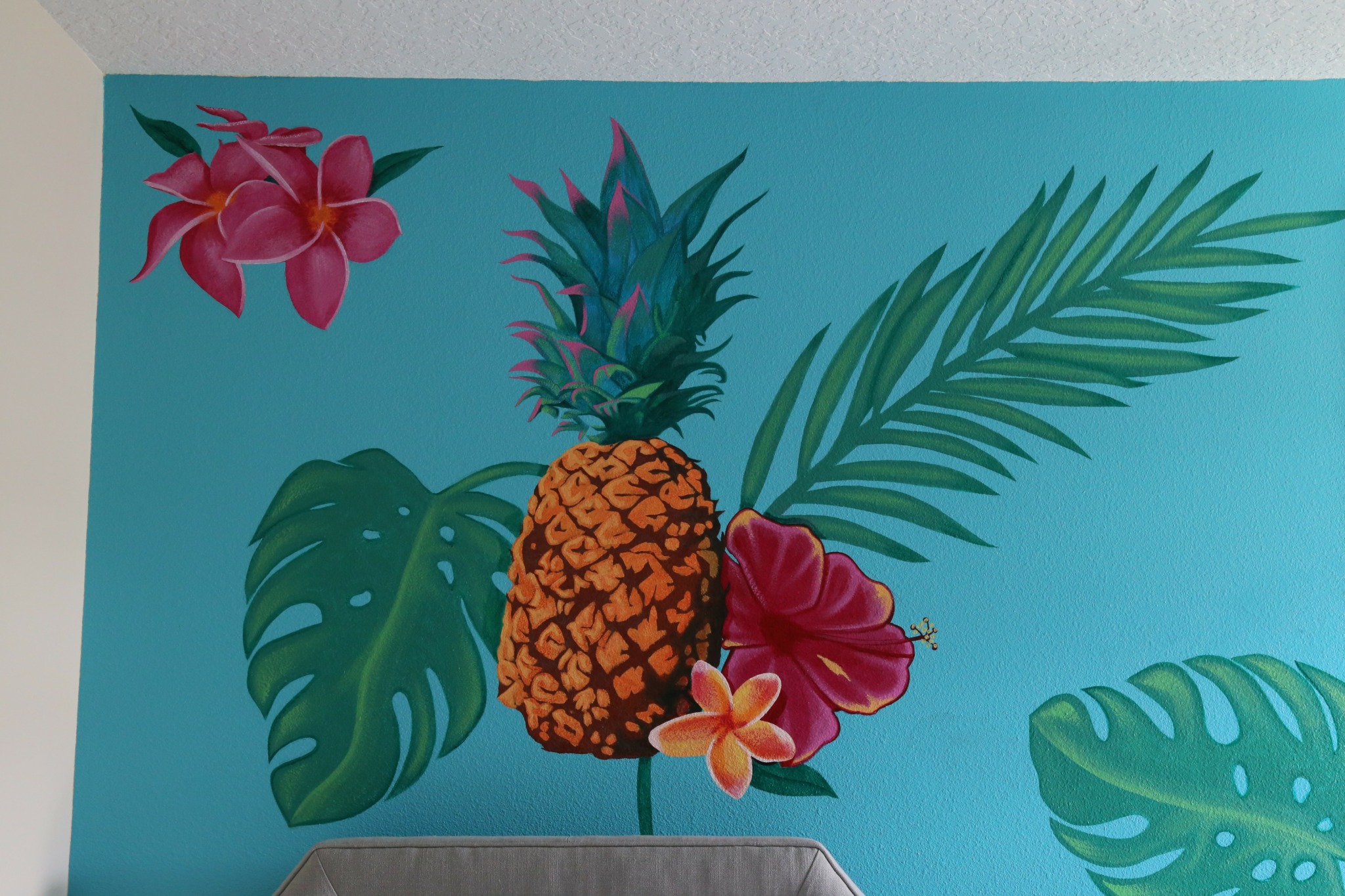 Colorful wall mural with pineapple, large leaves, and flowers on blue background.