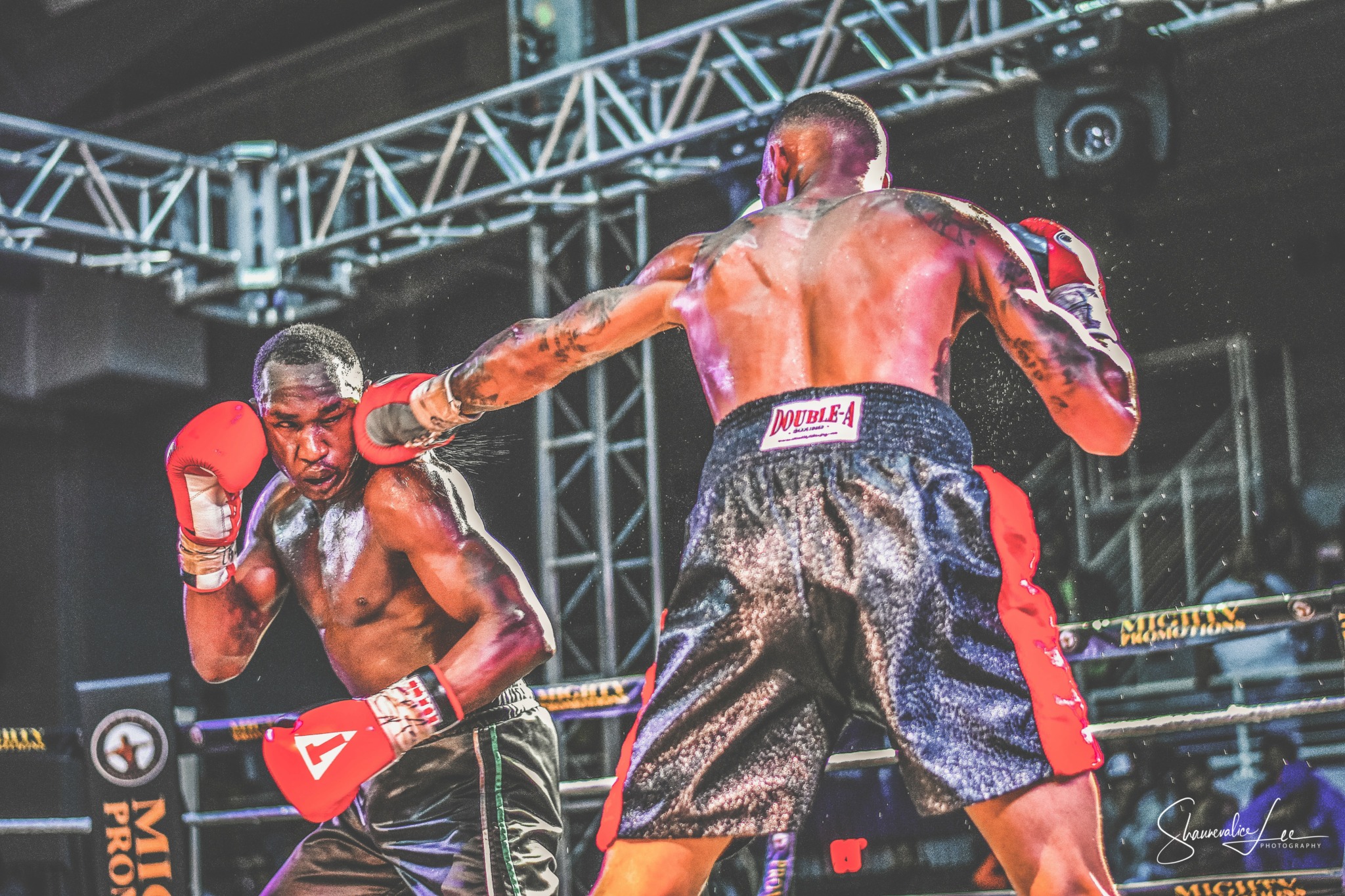 Two boxers in a ring, one throwing a punch at the other, with a metal structure overhead.