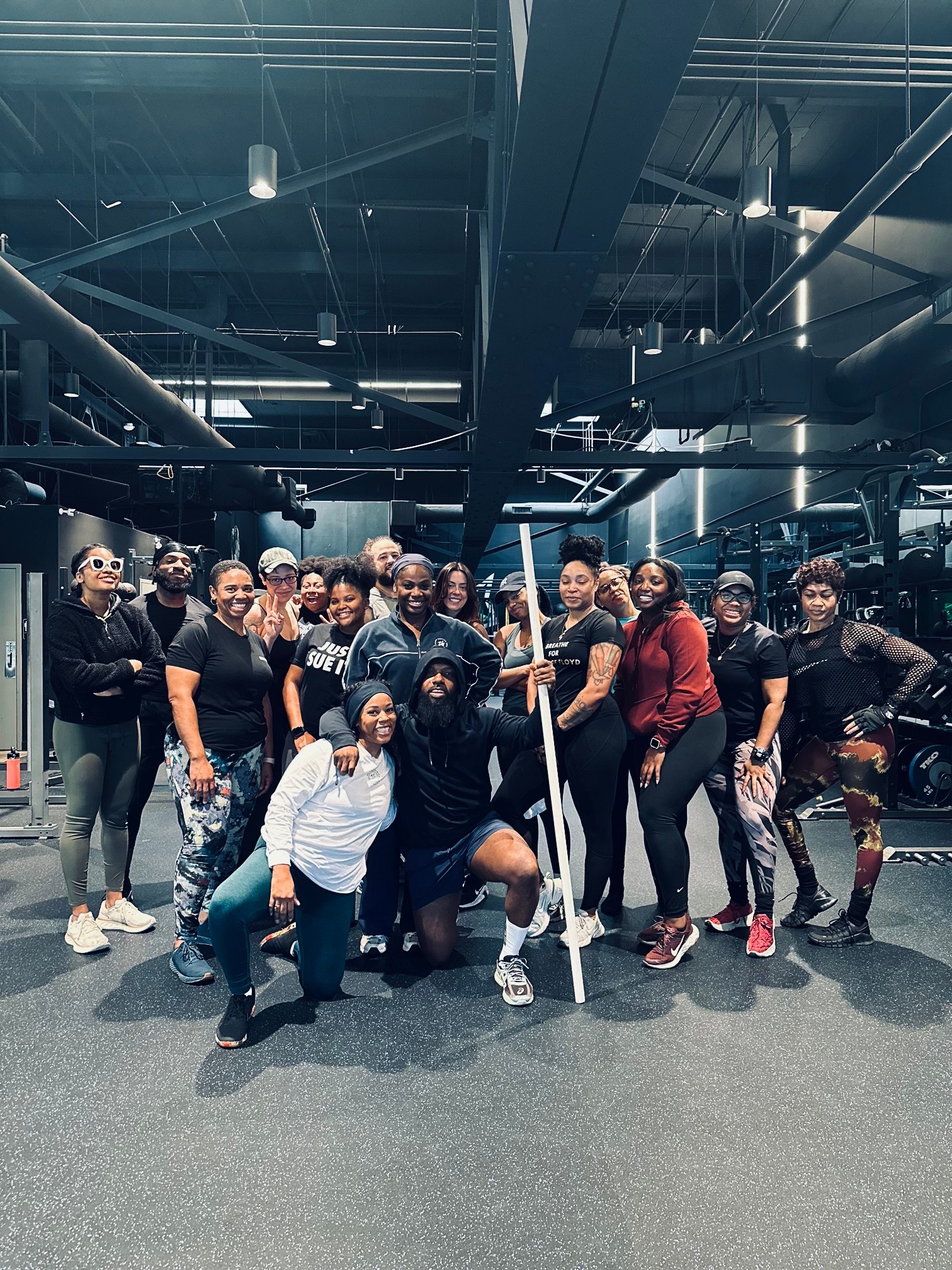 Group of people in an indoor parking garage, some holding a hockey stick, posing for a photo.