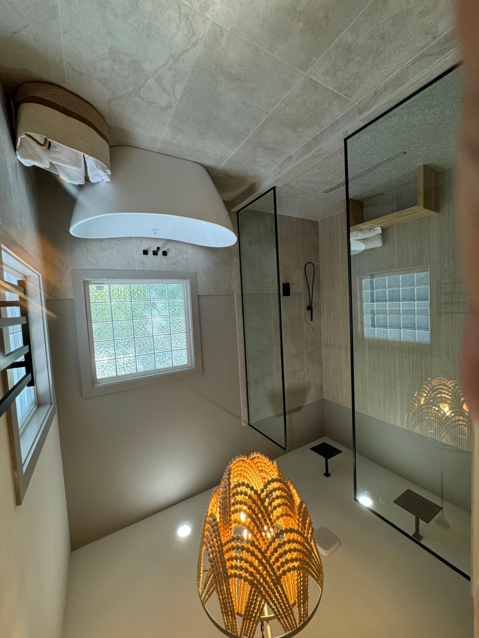 Bathroom with bathtub, window, glass shower door, and hanging light fixture.