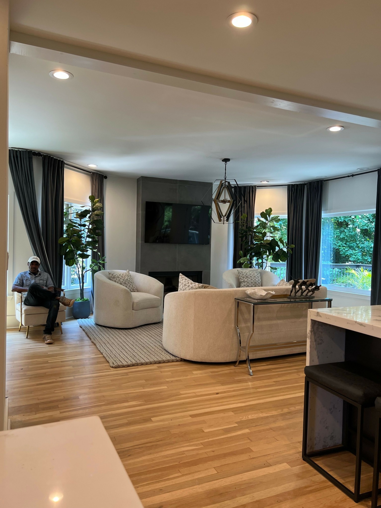 Living room with large window, two chairs, a small table, and a person standing near the window.