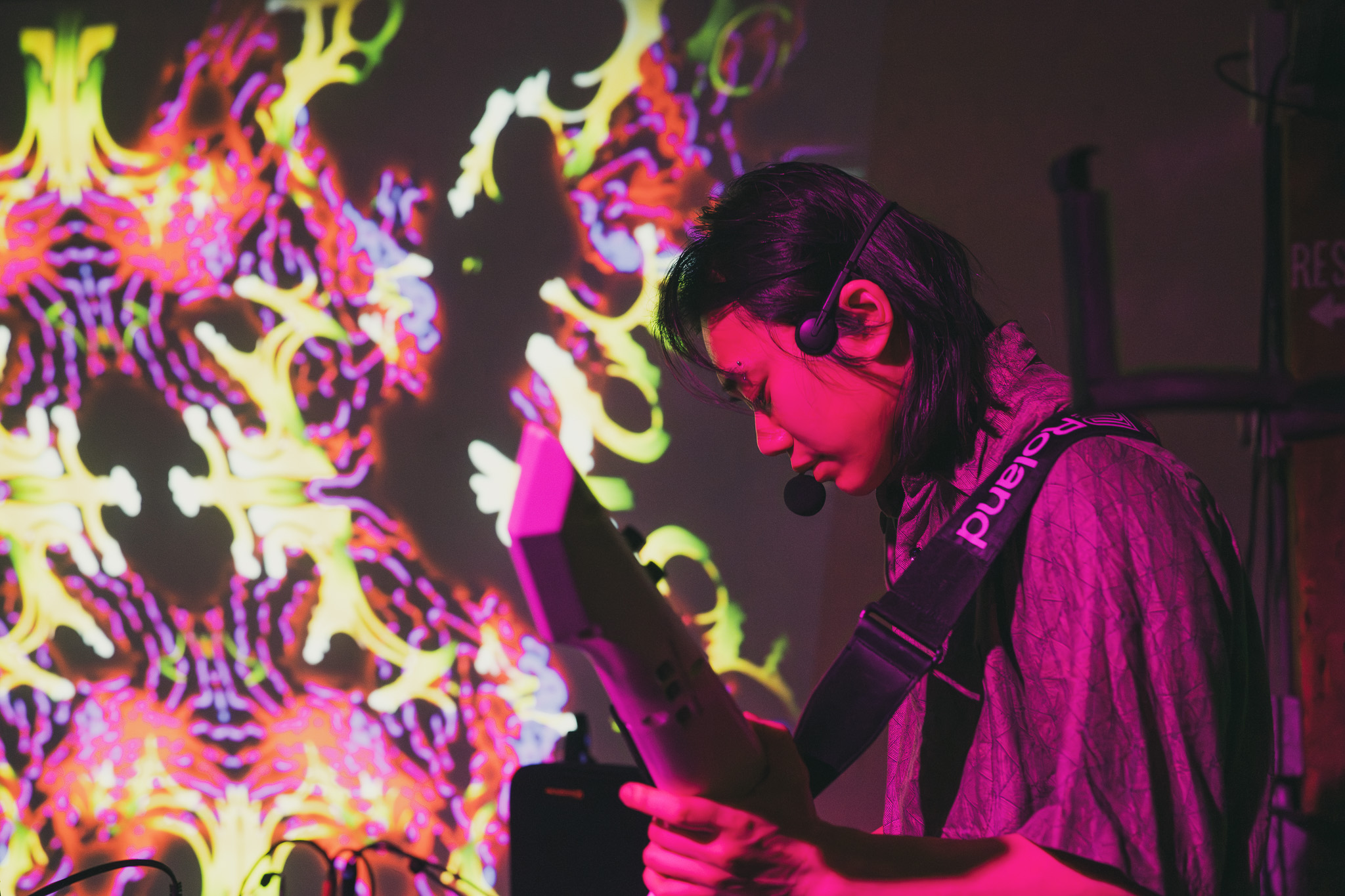 Person with glasses and dark hair looking at a tablet in front of colorful abstract background.