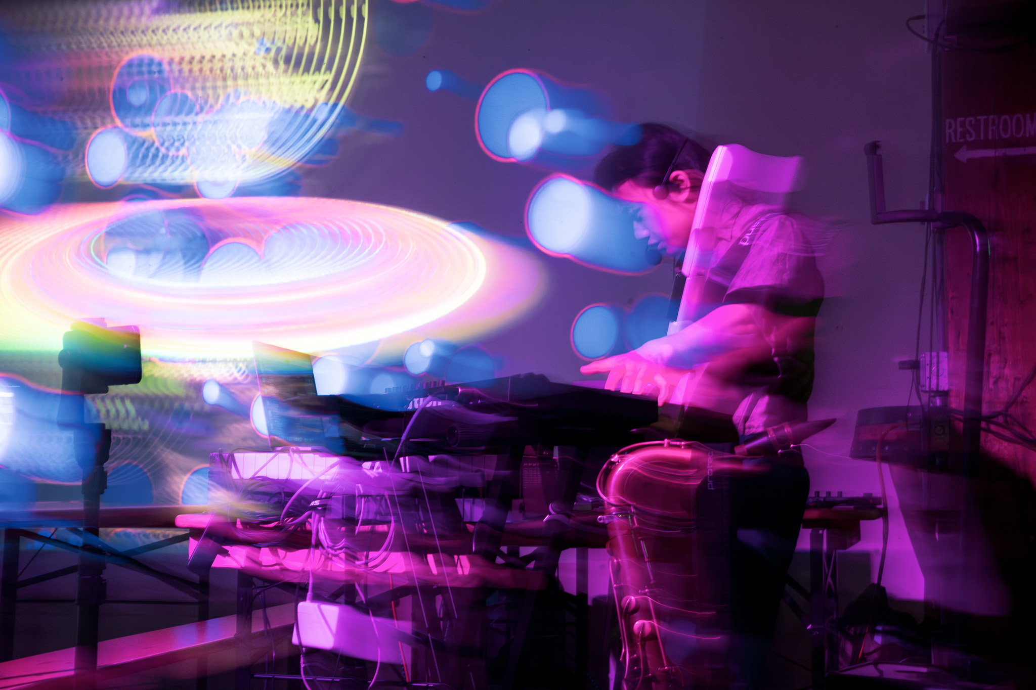 Person DJing with colorful light effects and blurred motion, creating a vibrant atmosphere.