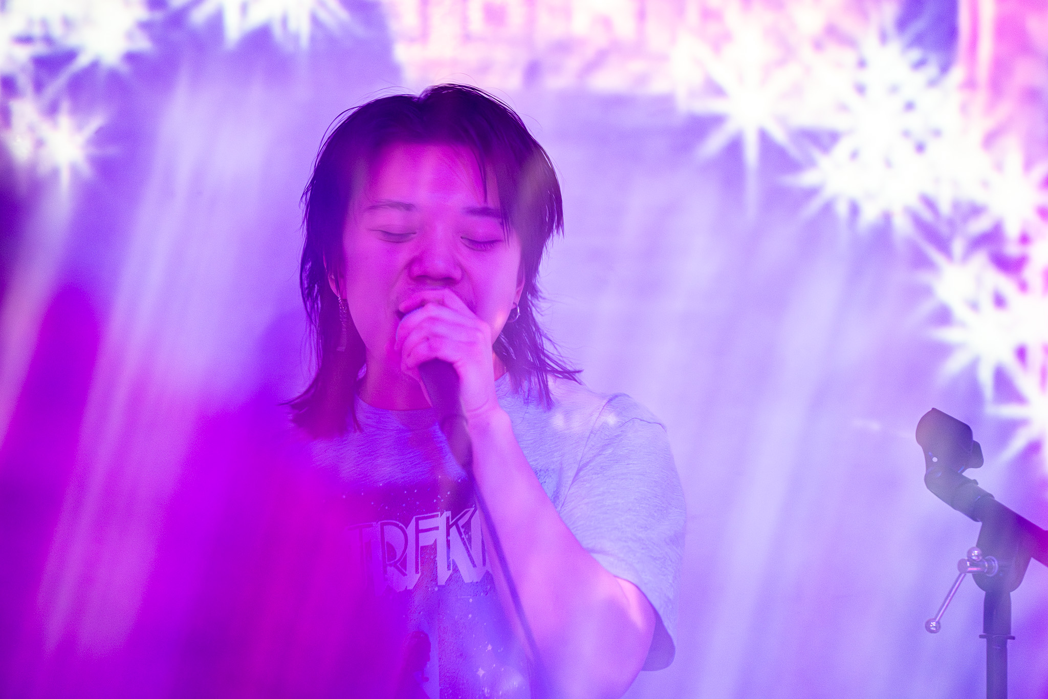 Person singing into a microphone with colorful, bright background lights and snowflake patterns.
