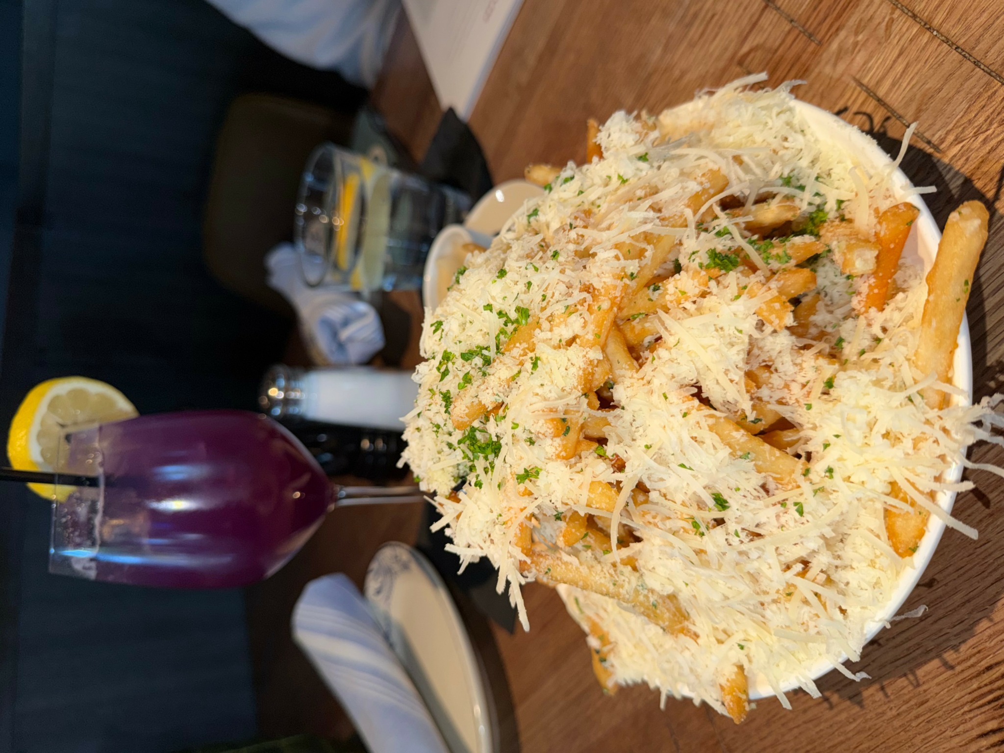 Large plate of shredded chicken salad with vegetables and cheese on a wooden table.