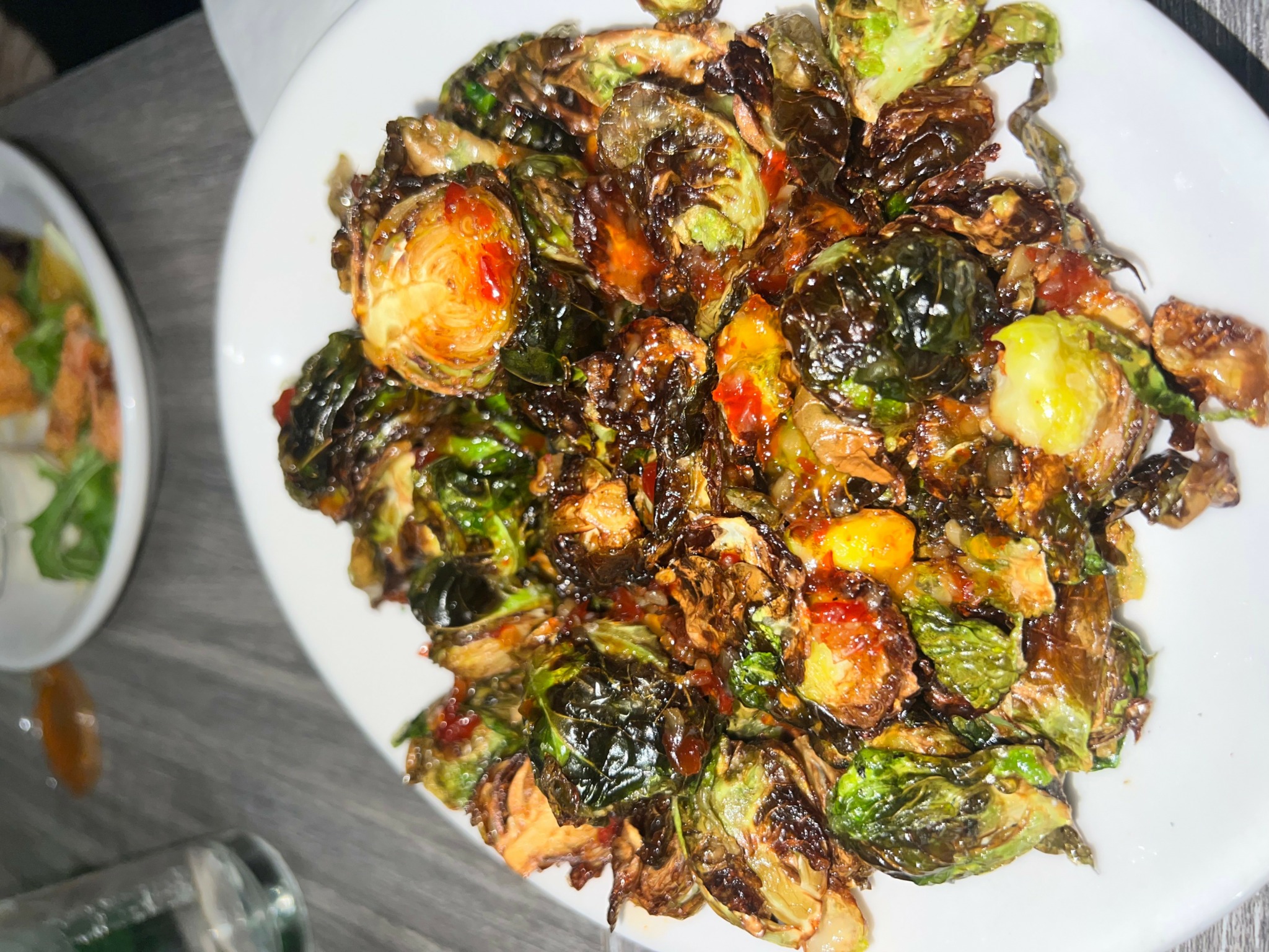 Plate of cooked bitter melon with dark, crispy edges and bright yellow and red accents.