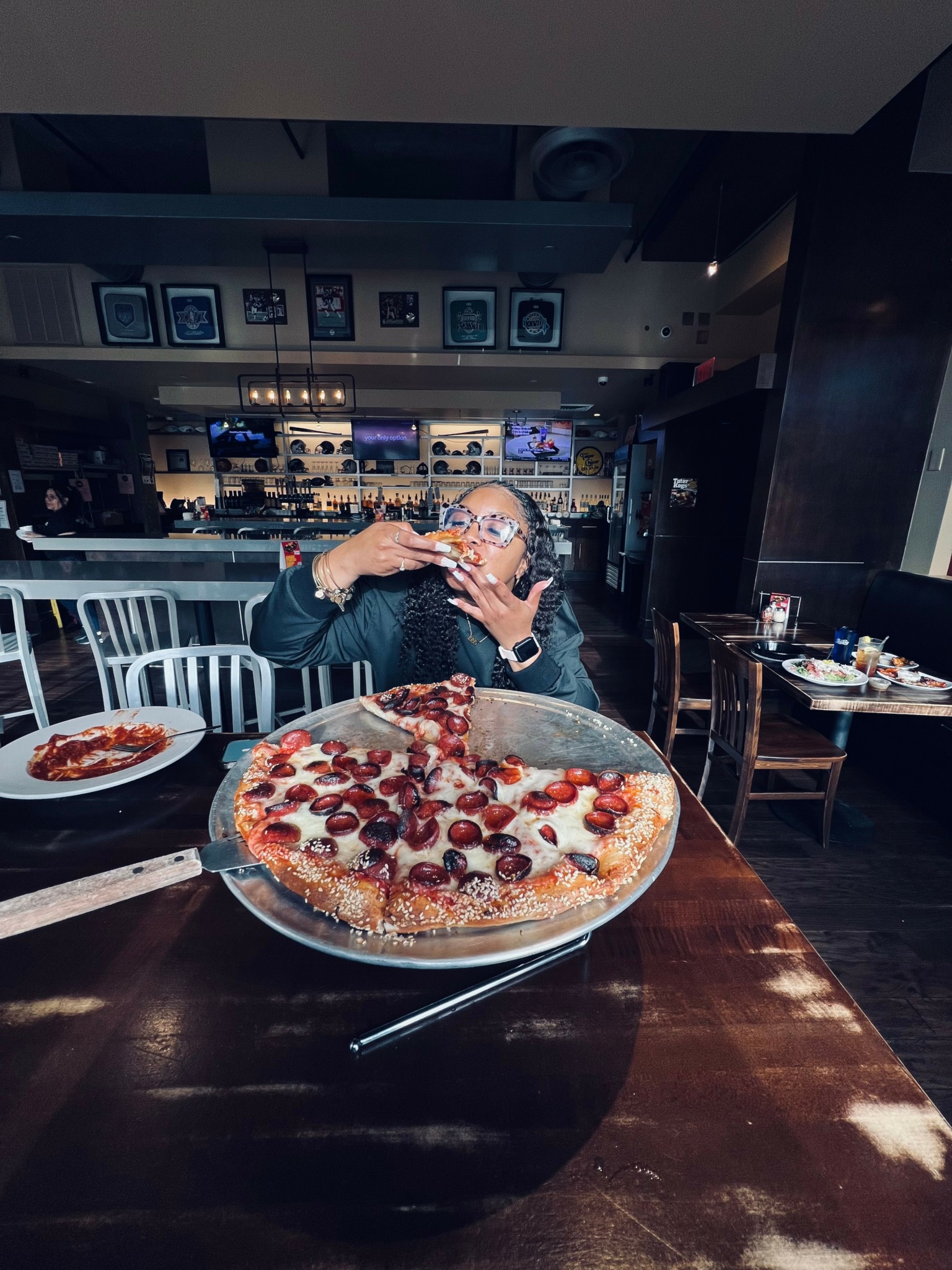 Person taking a photo of a large pizza with cherries on a table in a restaurant.