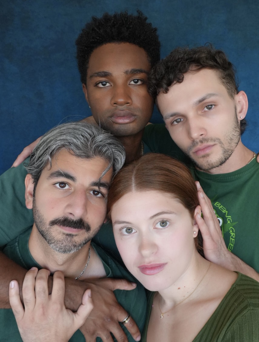 Group of four diverse people close together, looking at the camera, against a blue background.