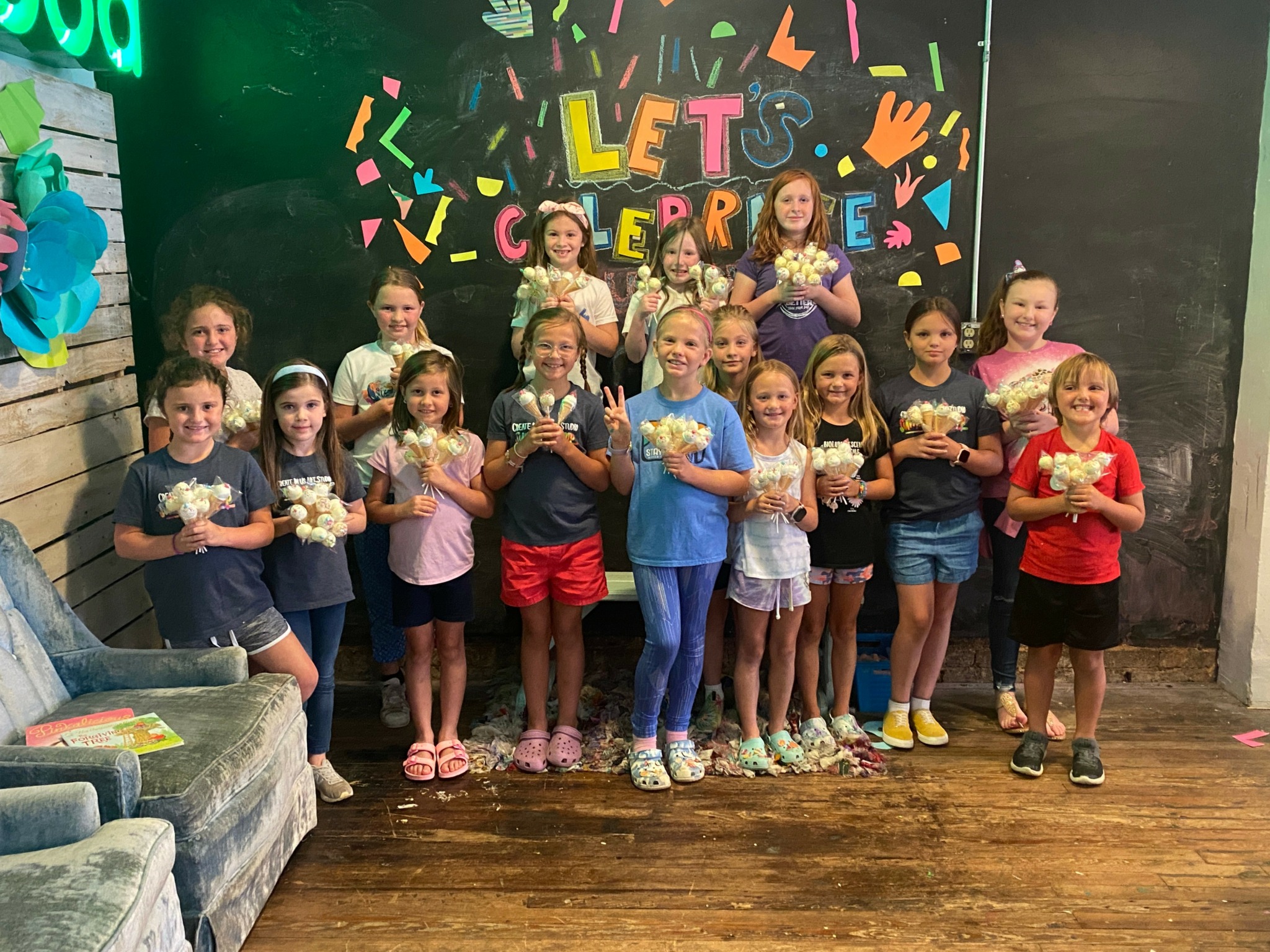 Group of children holding popcorn in front of colorful birthday celebration backdrop with confetti and 'Let's Celebrate' text.