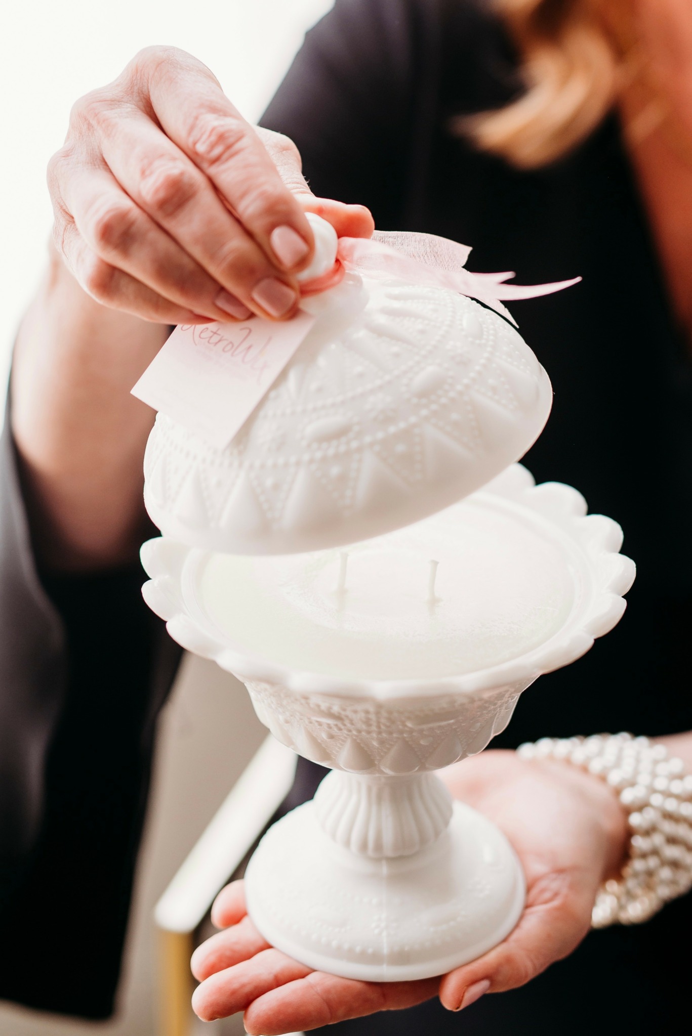Person holding a white decorative container with a lid, possibly for a wedding or special event.