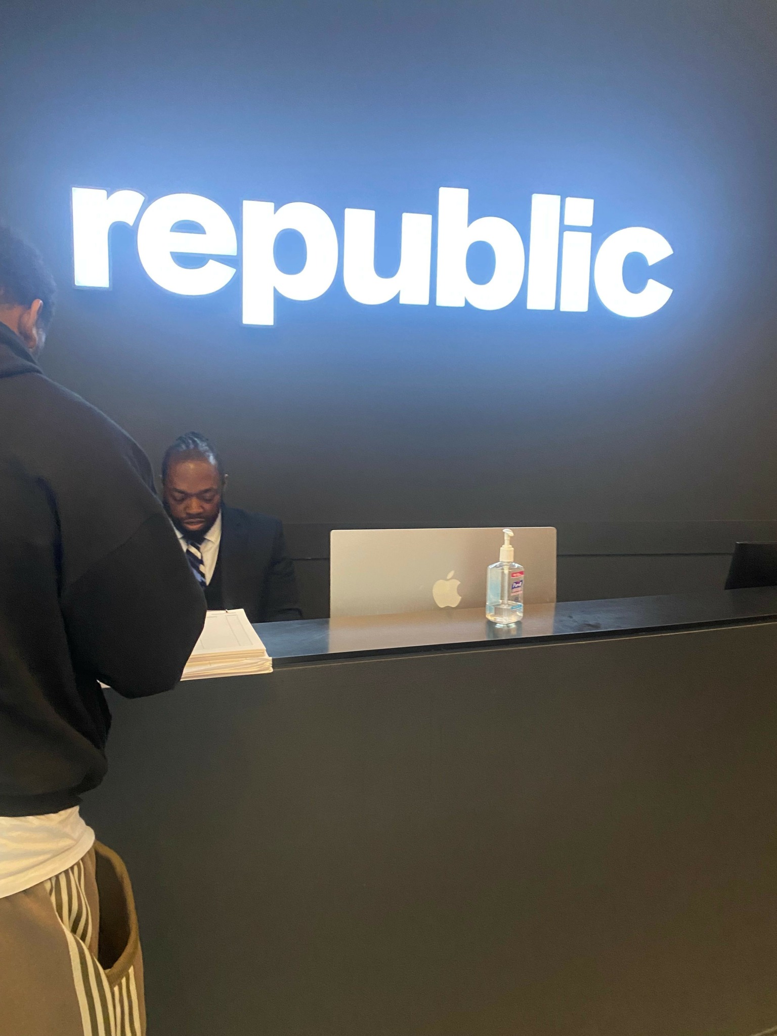 Person standing in front of a blue wall with the word 'republic' in white letters.