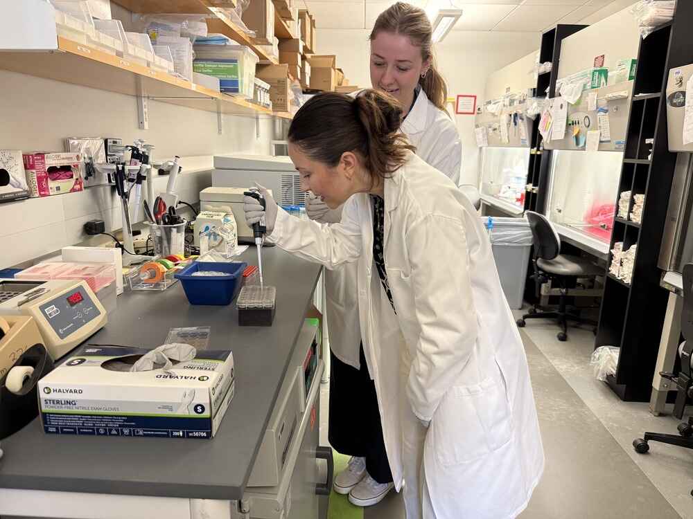 Two women in lab coats working with laboratory equipment in a laboratory setting.