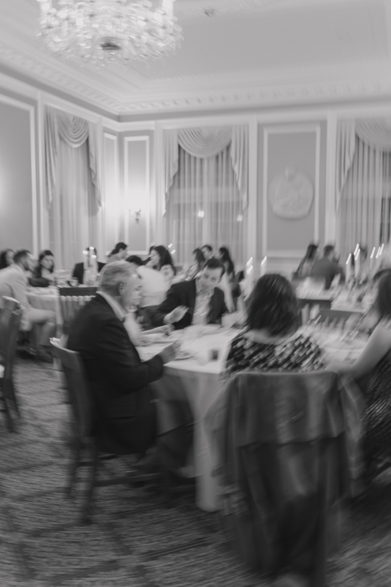 People seated at tables in a decorated banquet hall with ornate walls and curtains.