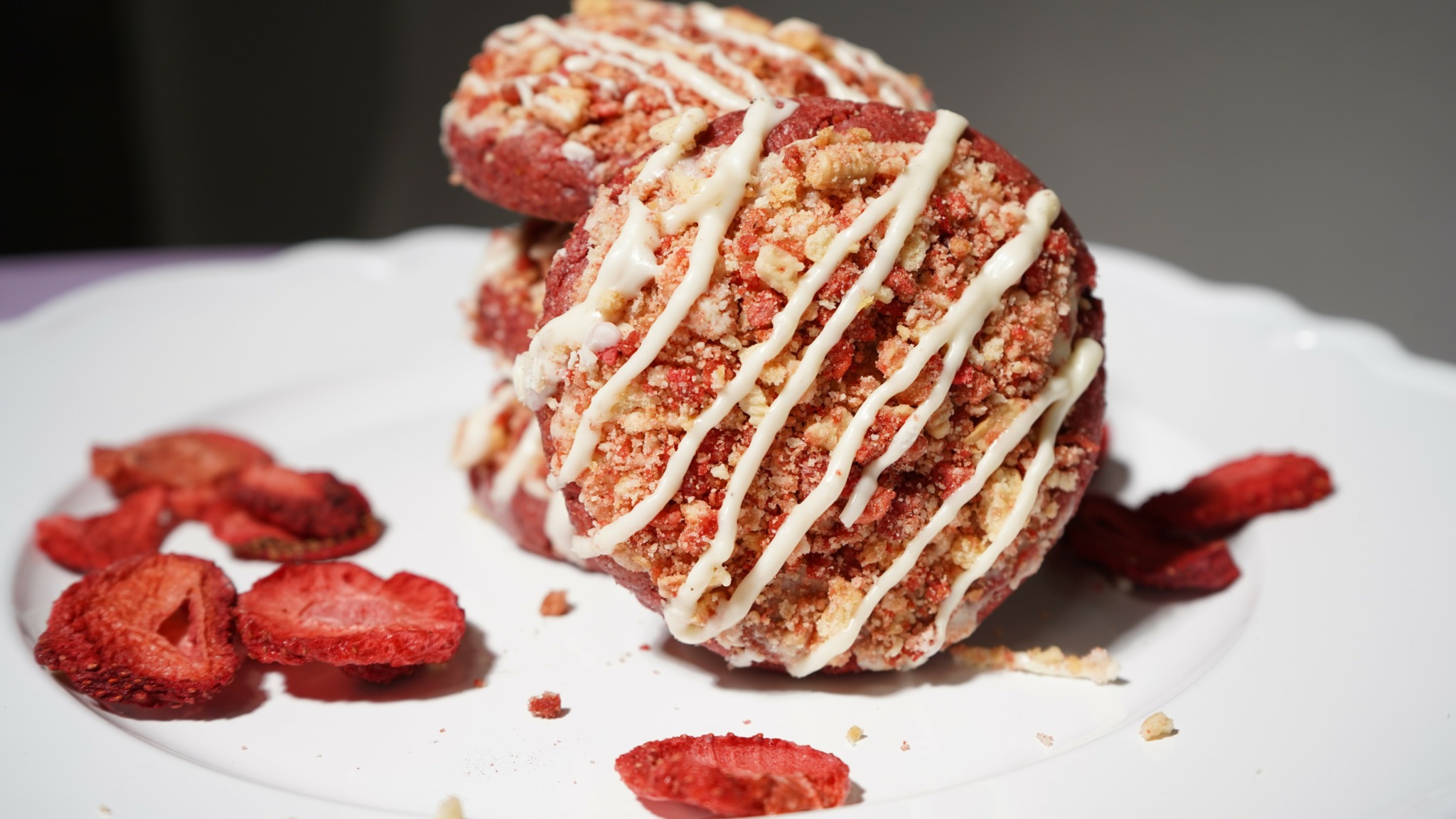 Fried dessert with white drizzle and sliced strawberries on a white plate.