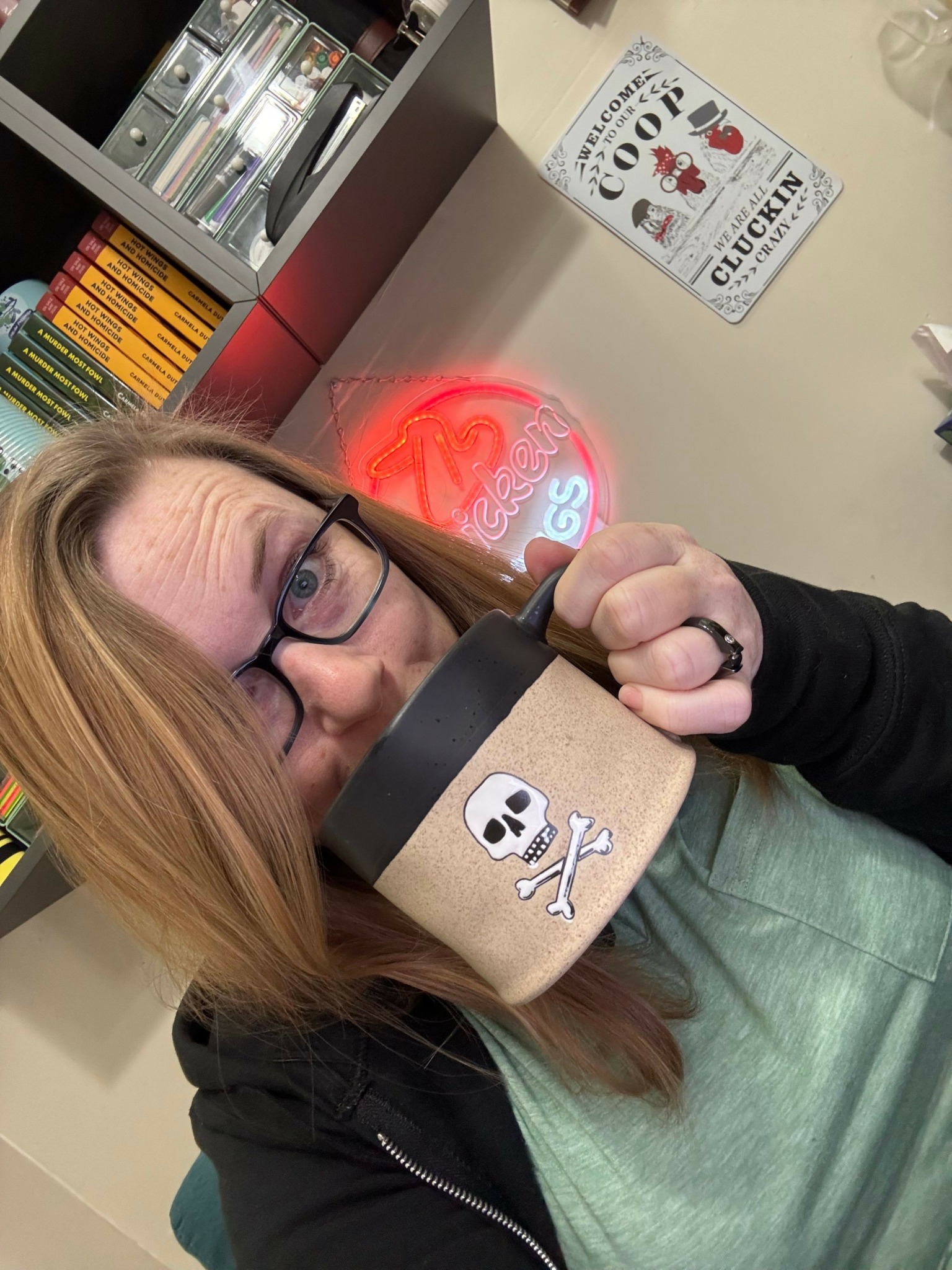 Person wearing glasses and a paper crown, holding a cup with a reindeer illustration, in a store setting.