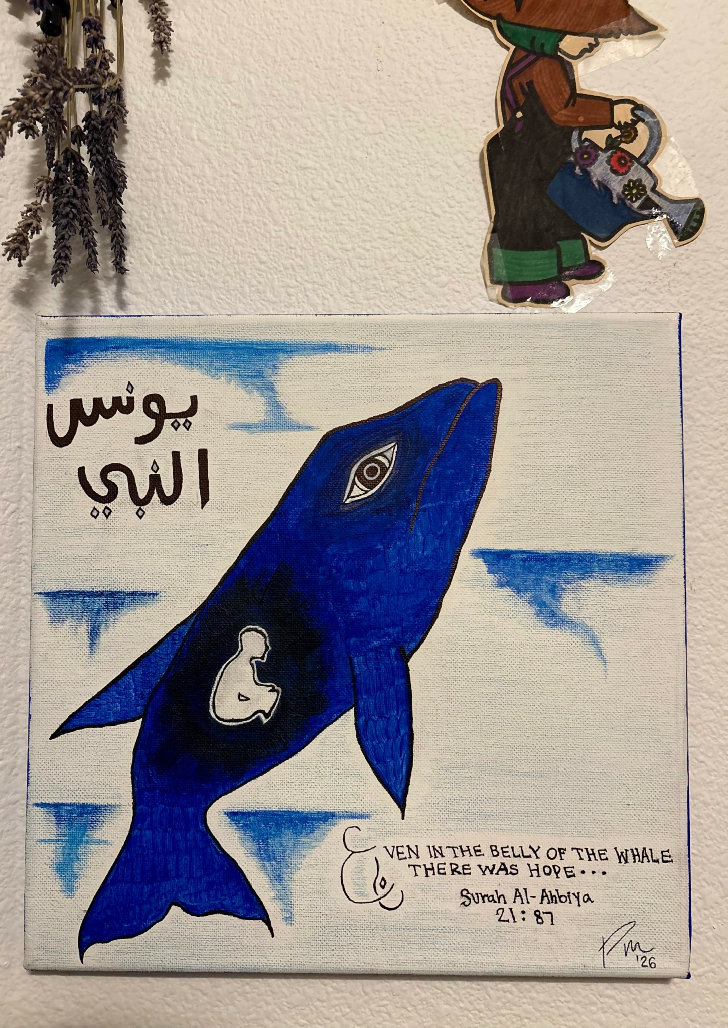 Blue fish with a white whale illustration on its side, Arabic text, and a handwritten note at the bottom.