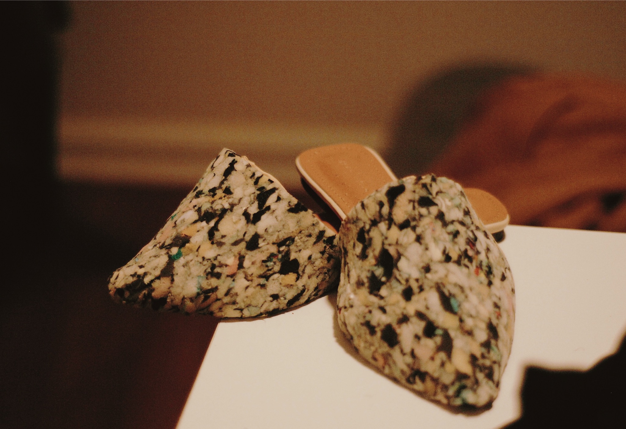 Two granola bars with wooden sticks on a white surface, blurred background, warm lighting.