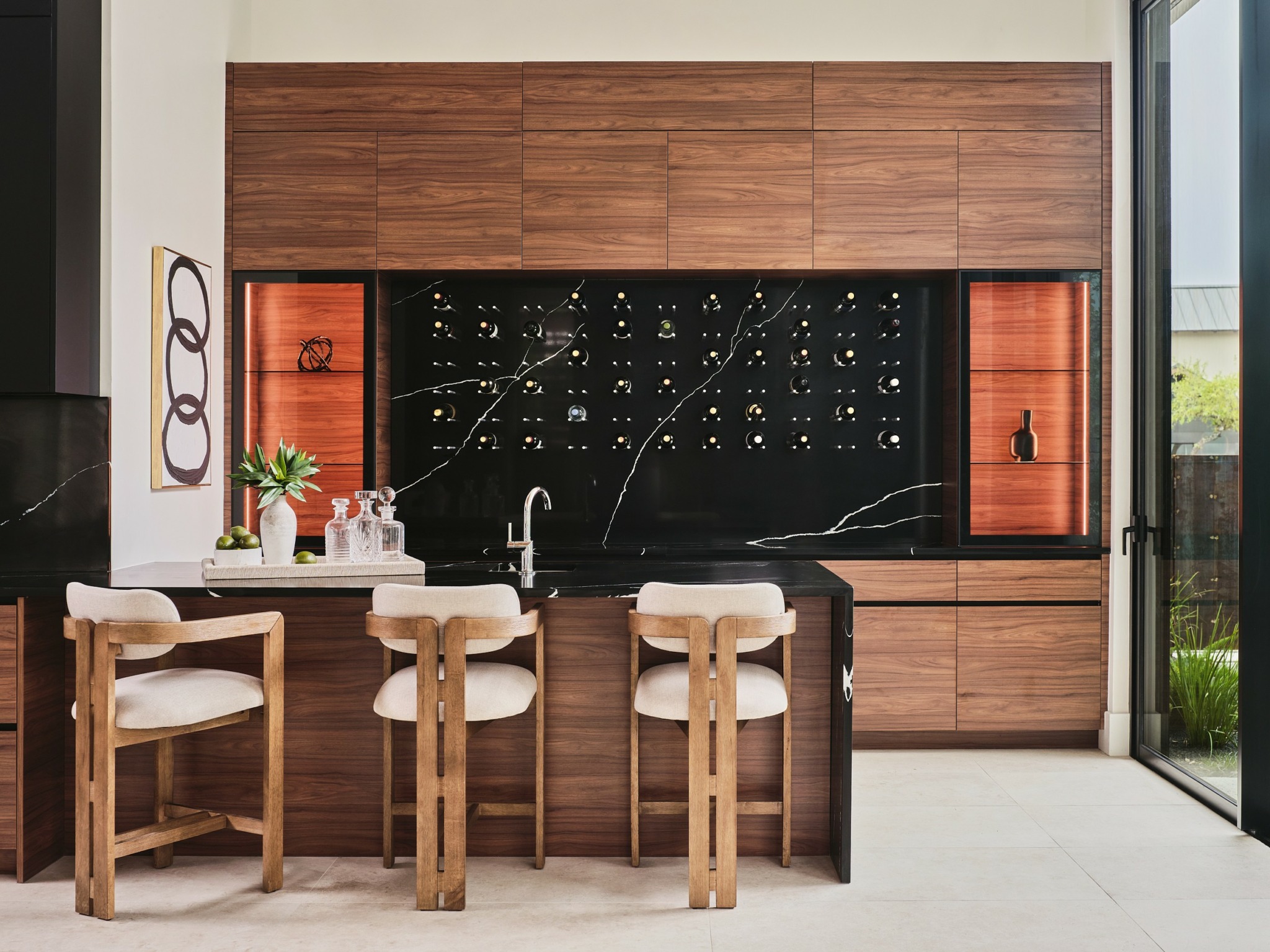 Kitchen with wooden cabinets, black backsplash, and a white countertop with four chairs, a sink, and decorative items.