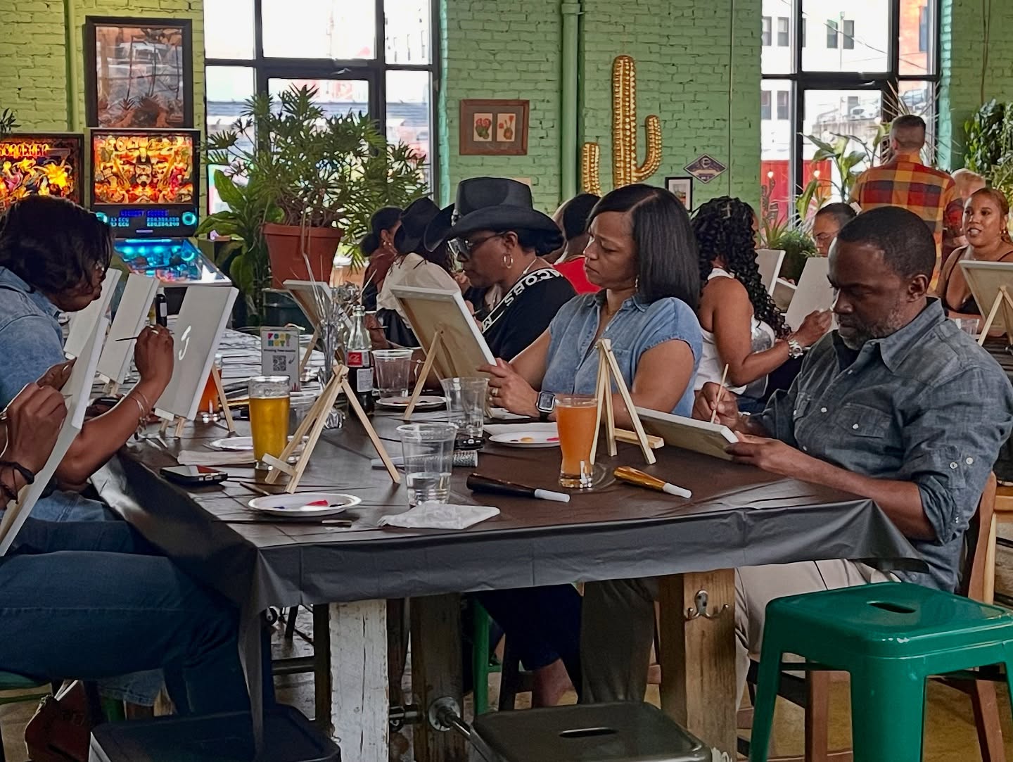 People sitting at a table in a cafe, working on laptops and reading, with drinks and glasses on the table.