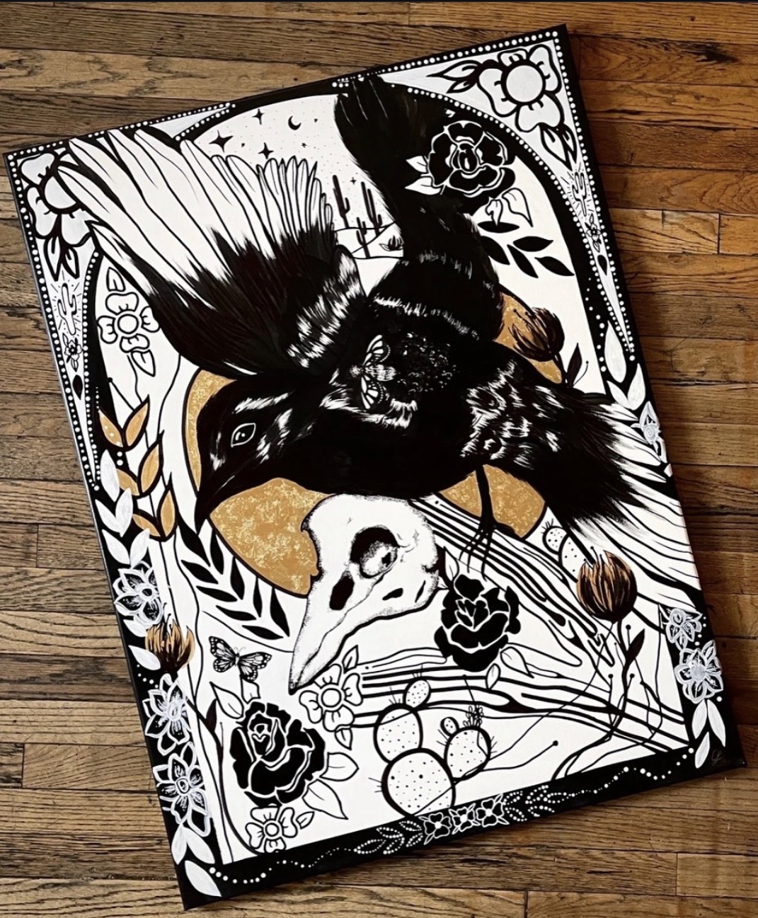 Coloring book page with a large bird, skull, roses, and decorative elements in black, white, and gold tones.