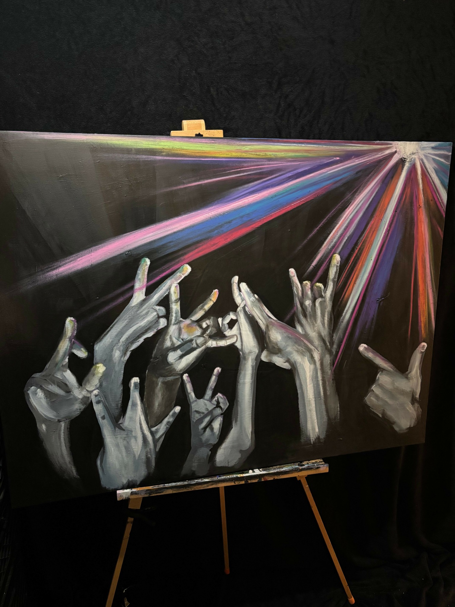 Multiple realistic hands reaching towards colorful light beams, with a dark background.