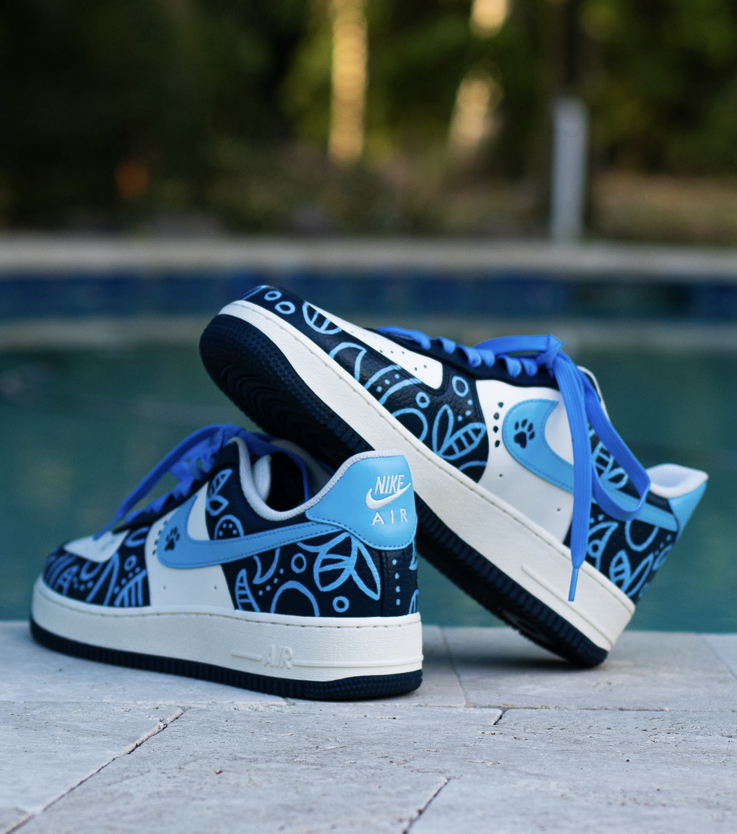 Pair of blue and white Nike sneakers with patterned design, placed on a poolside surface.