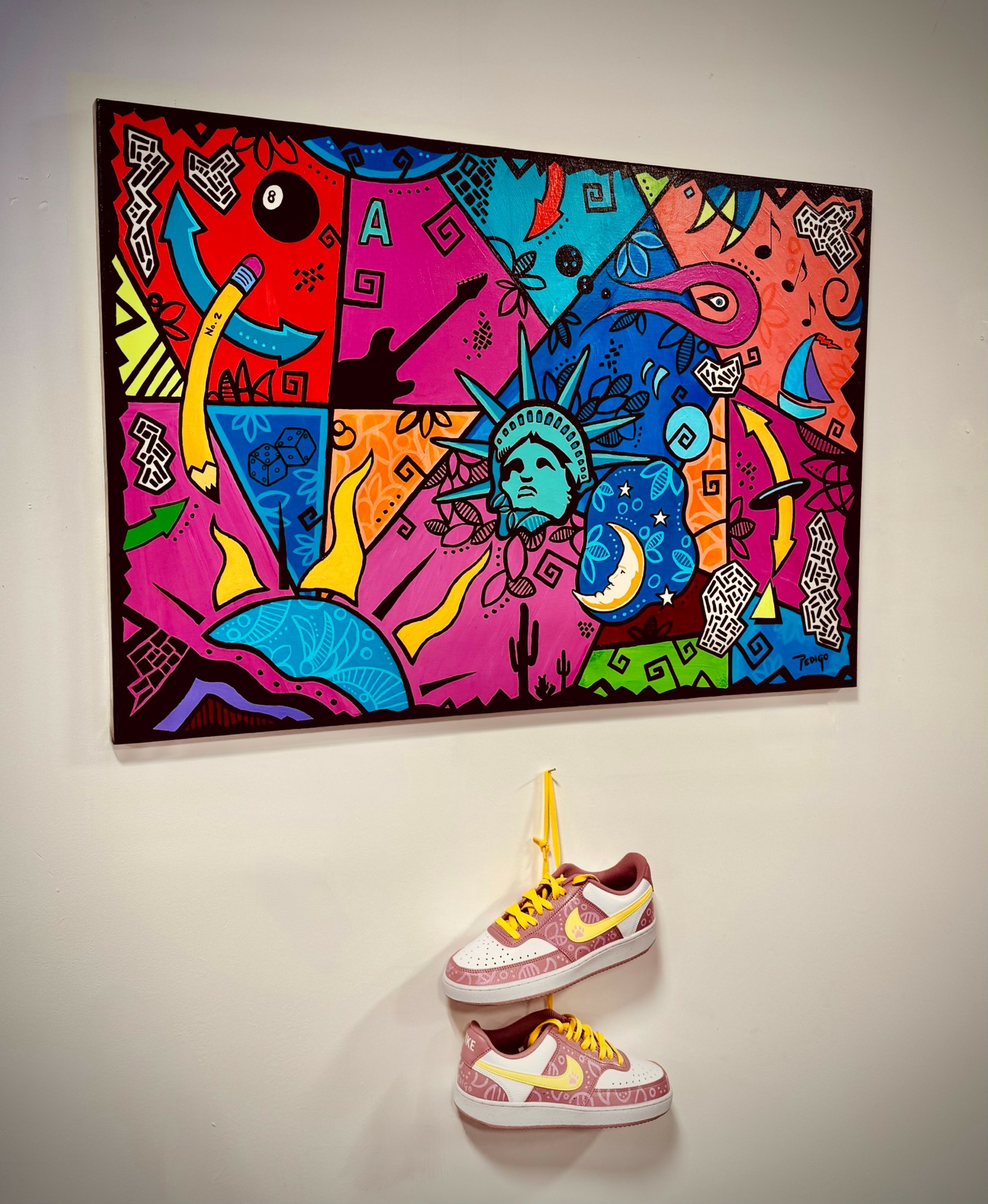 Colorful abstract painting with various shapes and patterns, including a face resembling the Statue of Liberty, displayed on a wall.