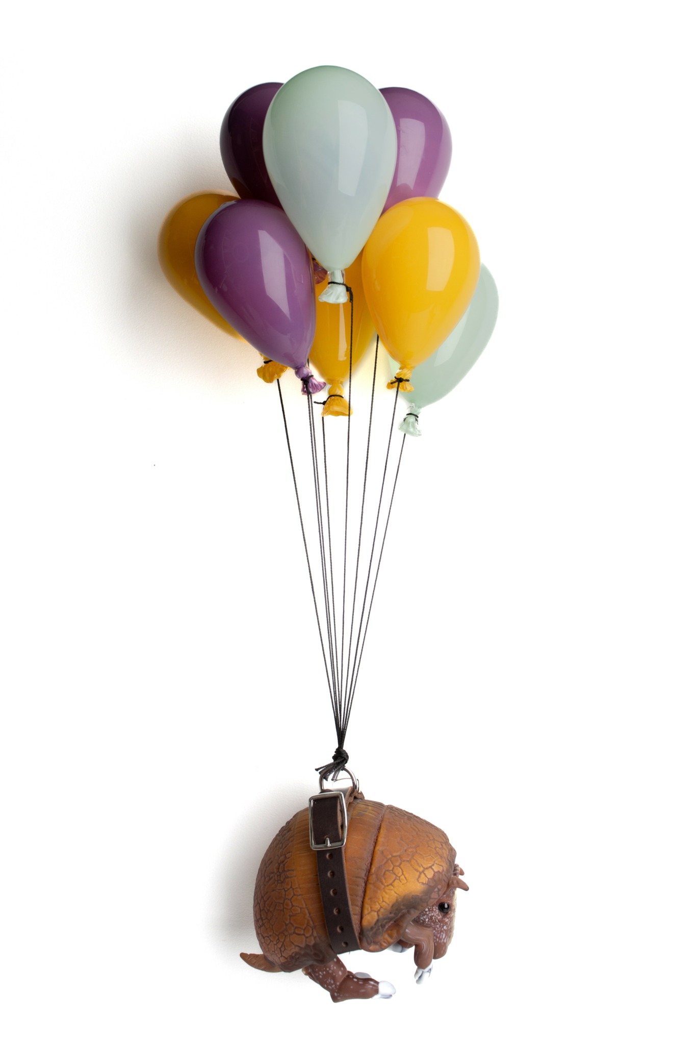 A hedgehog is suspended by balloons in various colors including purple, yellow, and light green.