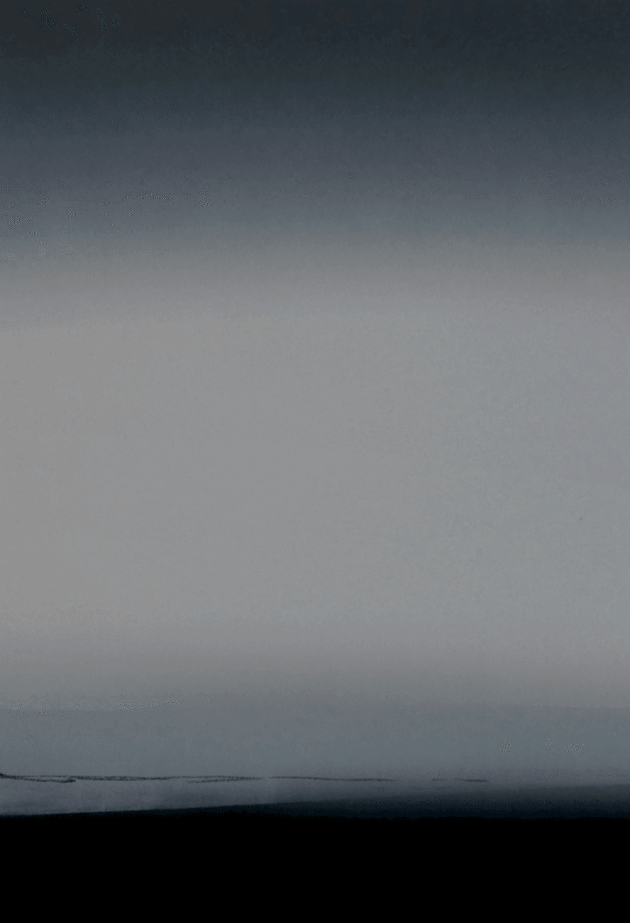 Blurred view of a landscape with a horizon and sky, no distinct objects visible.