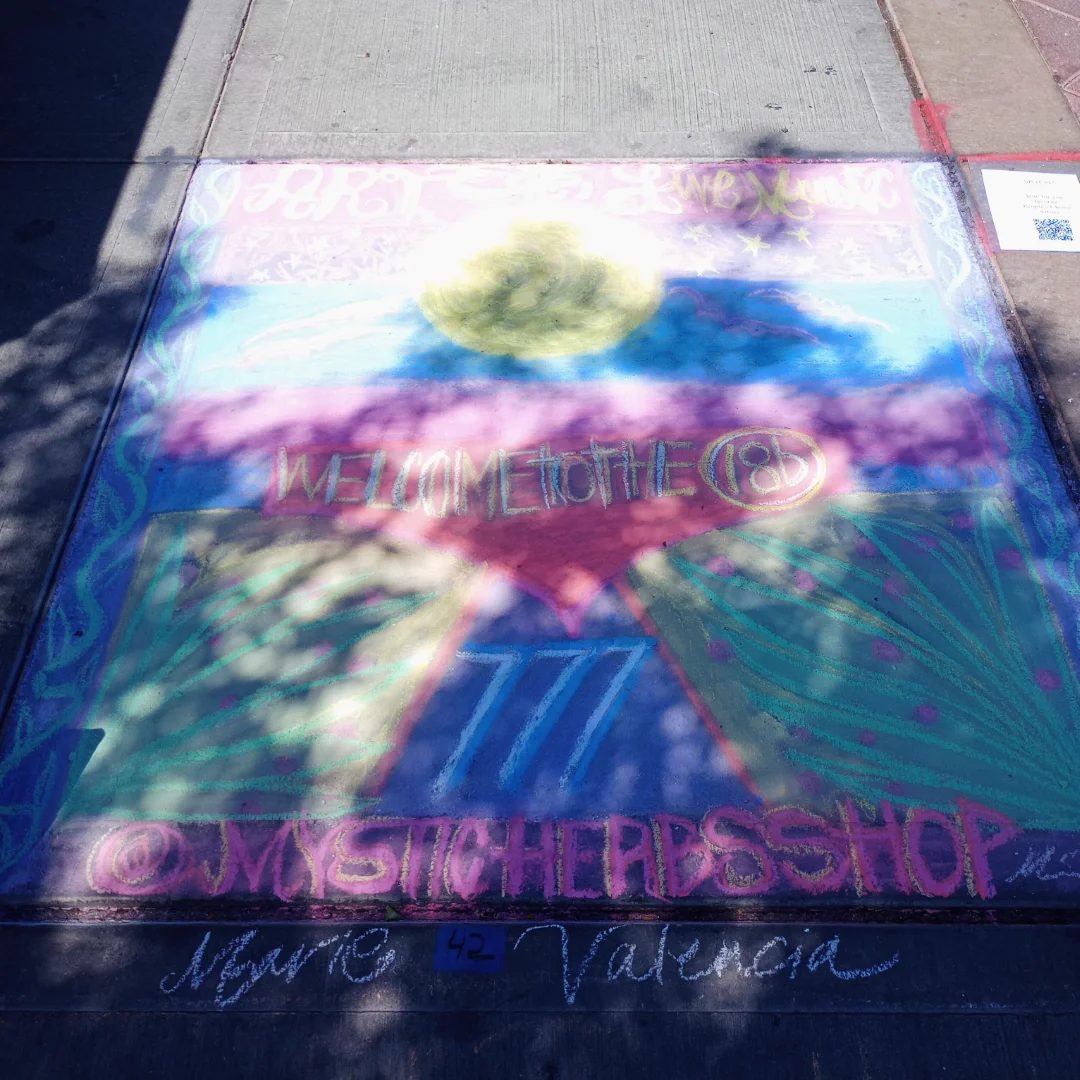 Colorful chalk art on sidewalk with text and designs, including a heart and flowers.