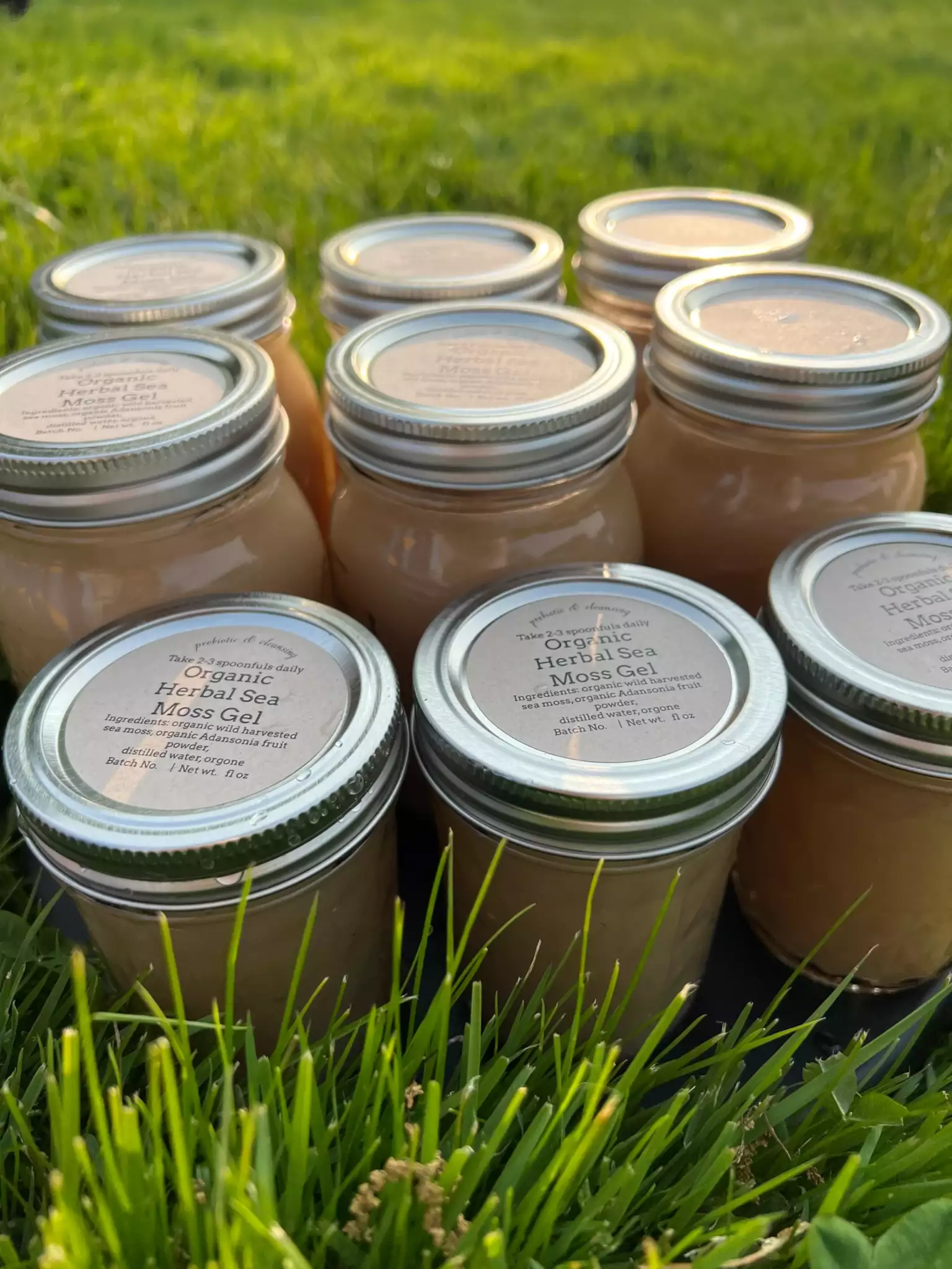 Multiple jars of caramel fudge ice cream placed on grass with a blurred green background.