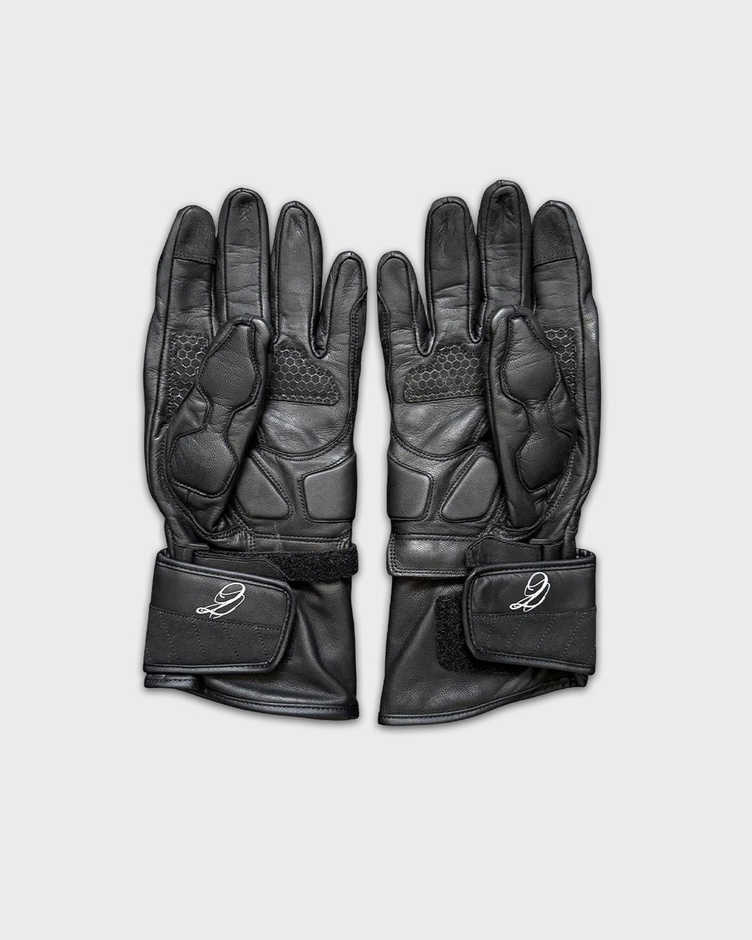 Pair of black gloves with textured and padded areas, laid flat on a light background.