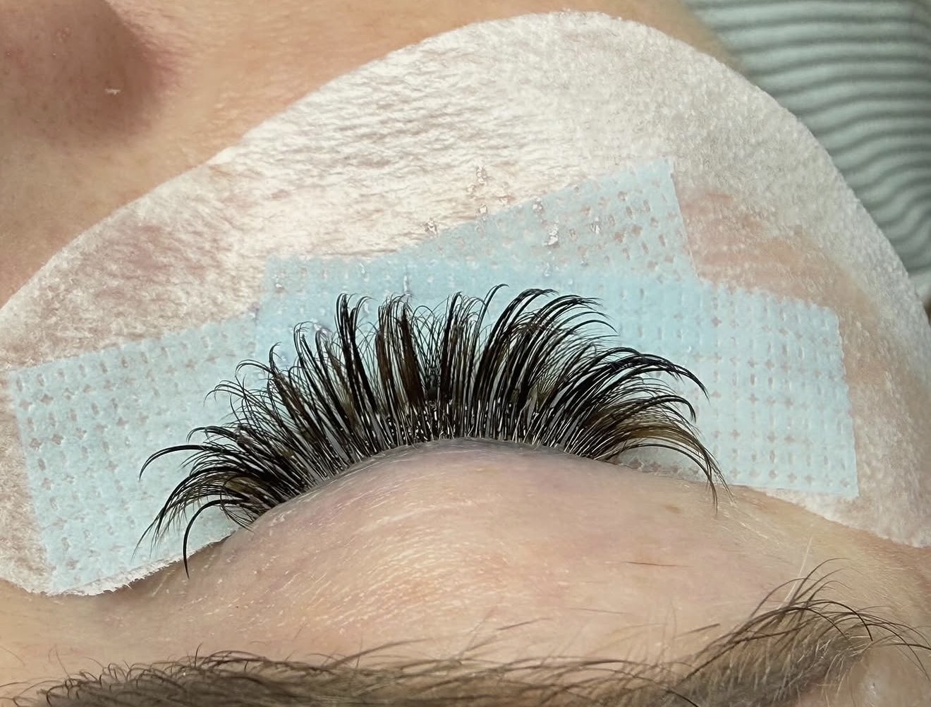 Eyelash extension application on a person's eye with a protective pad underneath.