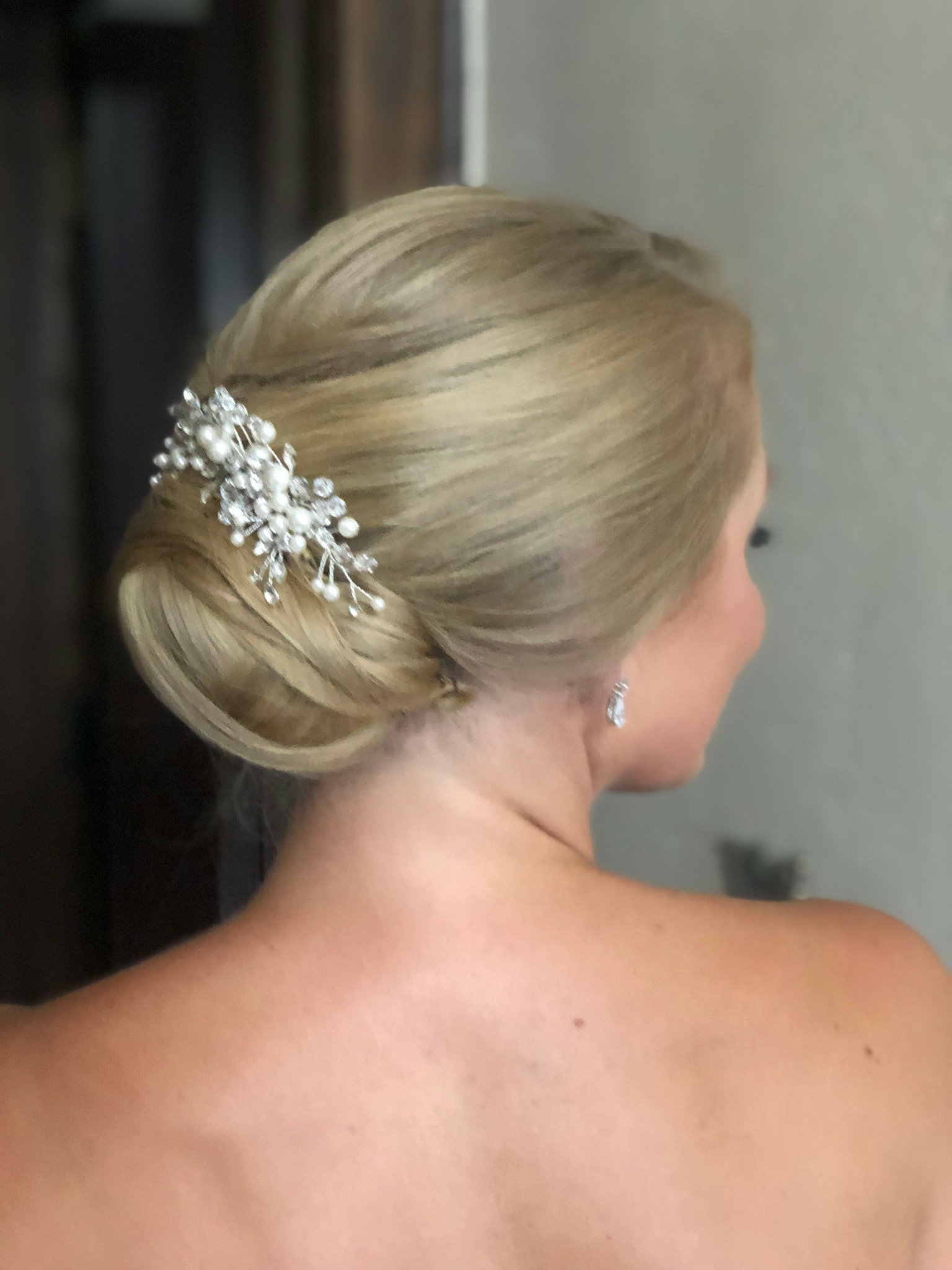 Back view of a woman with blonde hair styled in an elegant updo with a decorative hair accessory.
