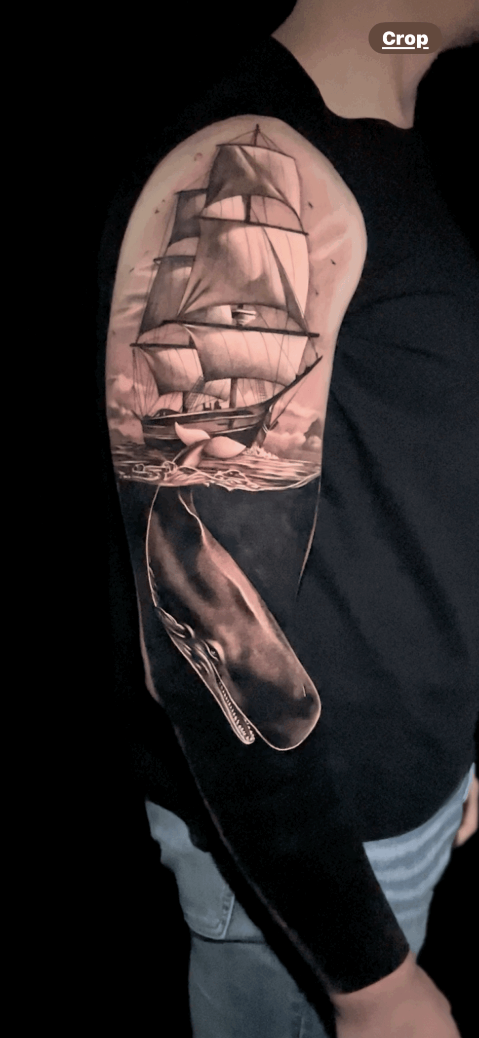 Tattoo of a sailing ship on person's upper arm with detailed sails and hull.