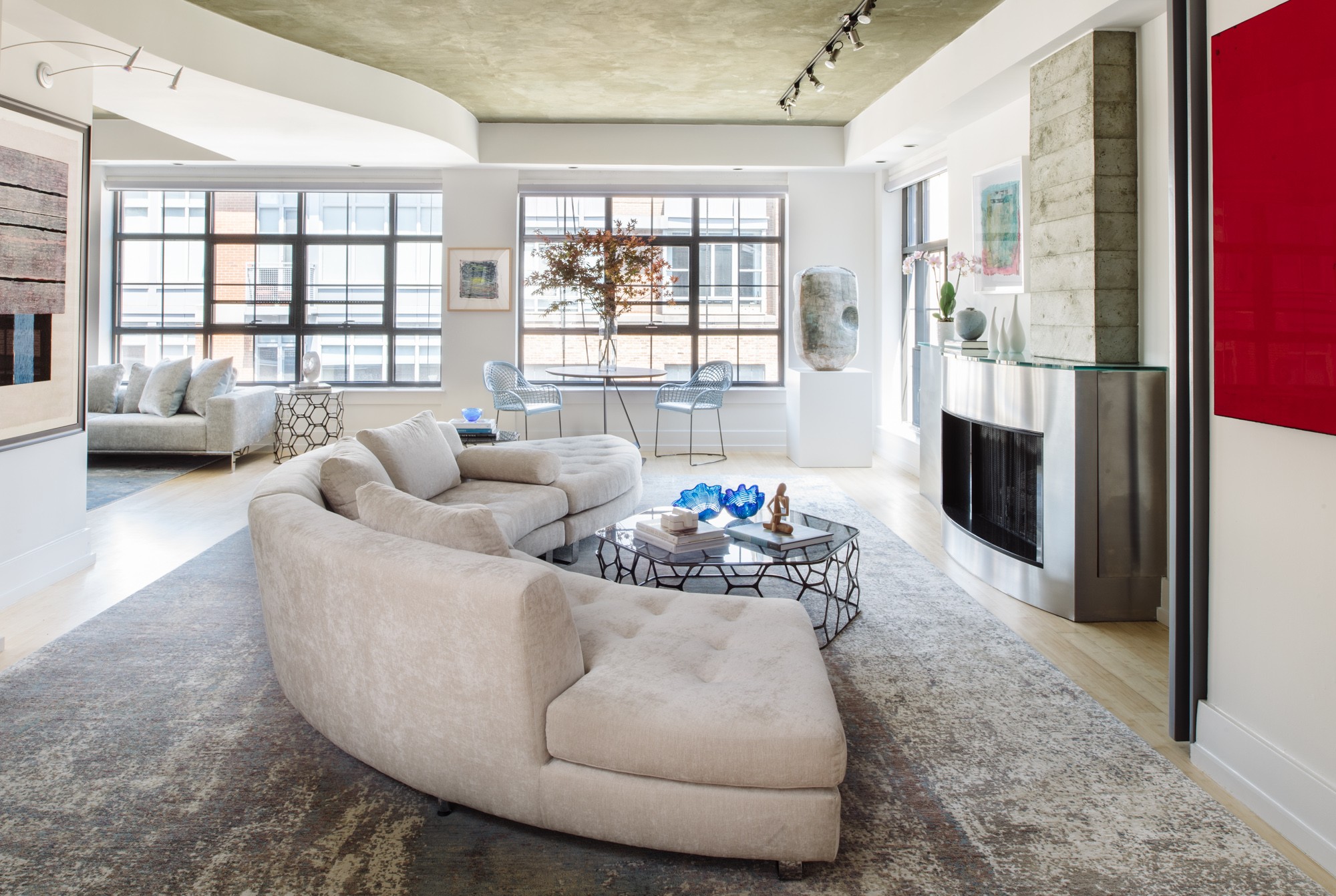Spacious living room with curved sofa, large windows, fireplace, and modern decor.