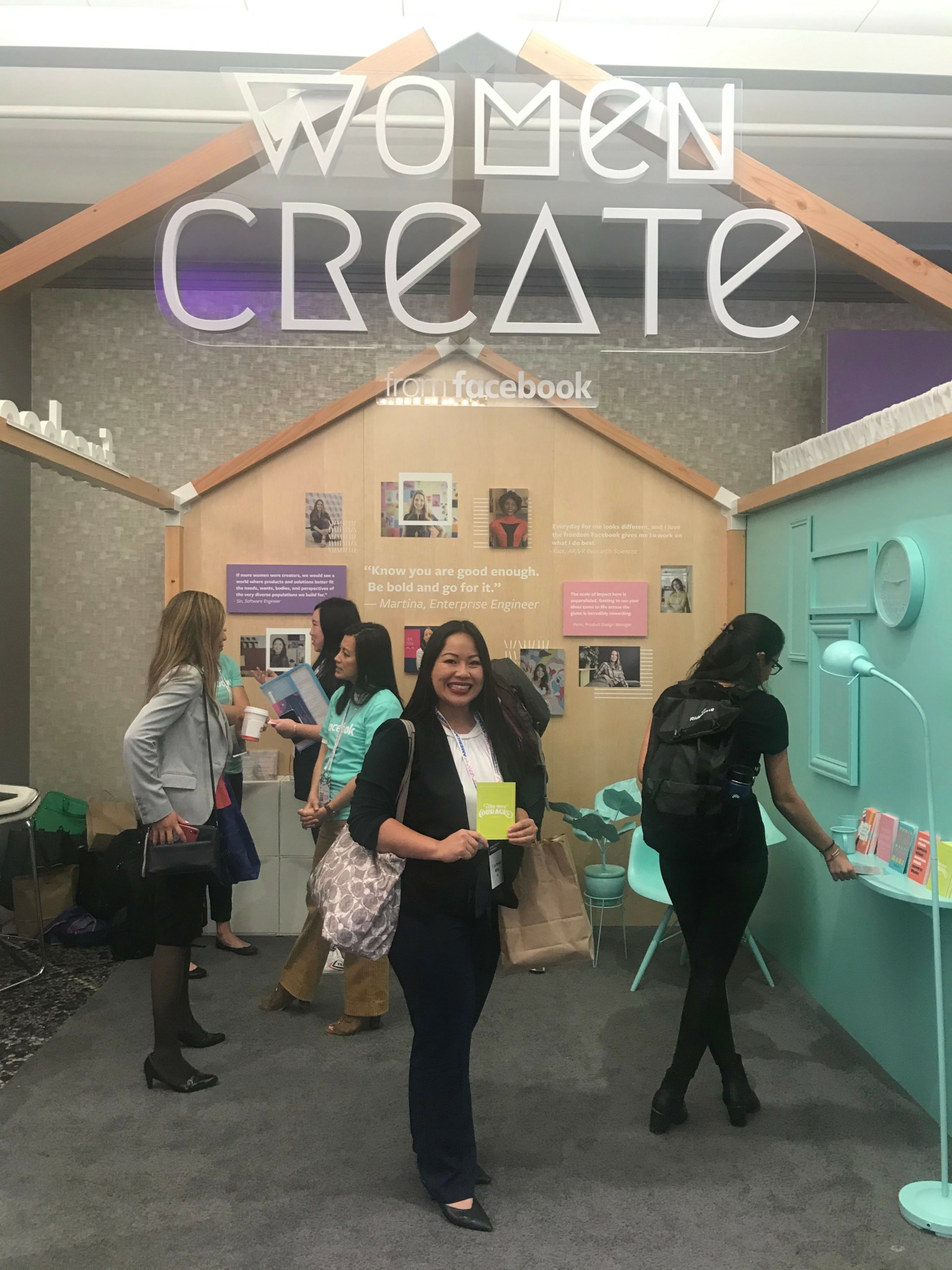 Group of women at an event with a backdrop reading 'Women Create' and Facebook logo, engaging with displays.