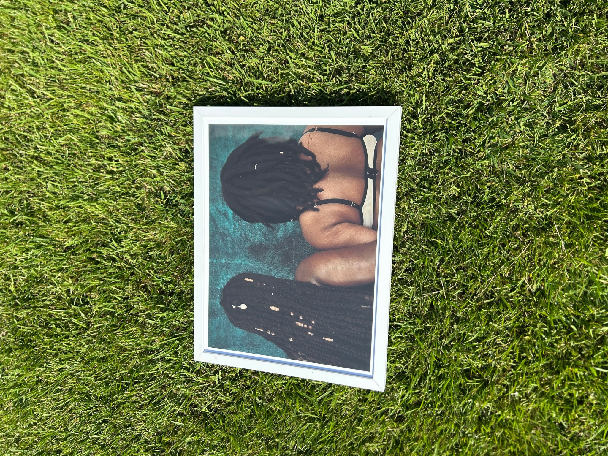Person with long dark hair lying on a blue surface, facing away, with arms bent and head down.