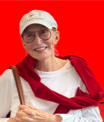 Smiling woman wearing glasses, white cap, white shirt, and red sweater draped over shoulders, against a red background.