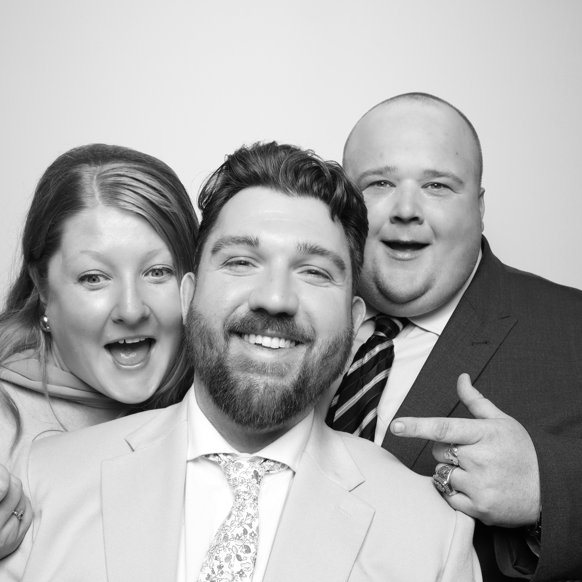 Three people smiling, two men and one woman, posing together in formal attire.